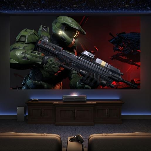 Gracz w ciemnym pokoju oglądający duży ekran z rozgrywką Halo.