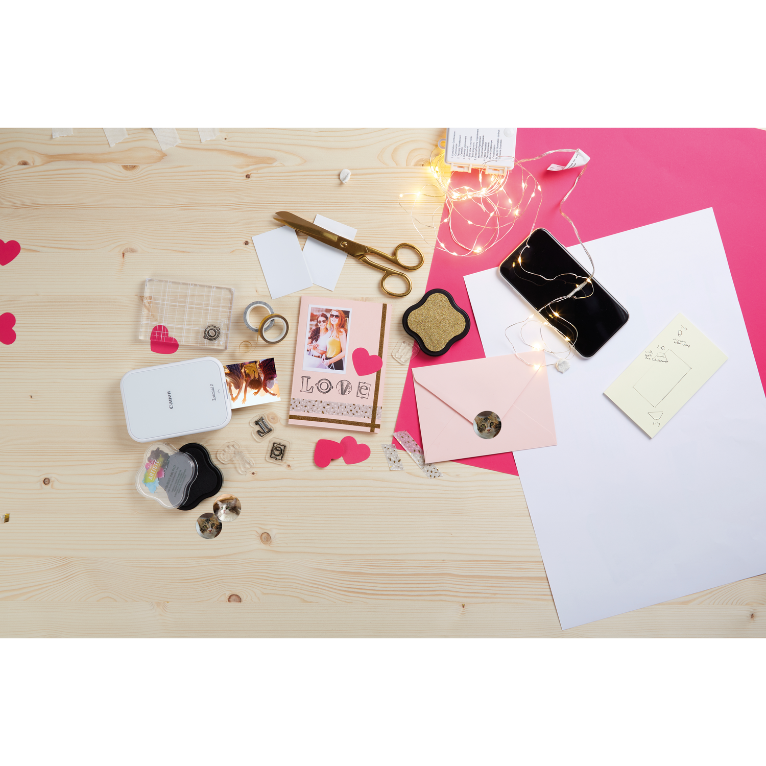 Crafting supplies on a wooden table: photos, scissors, lights, and more.