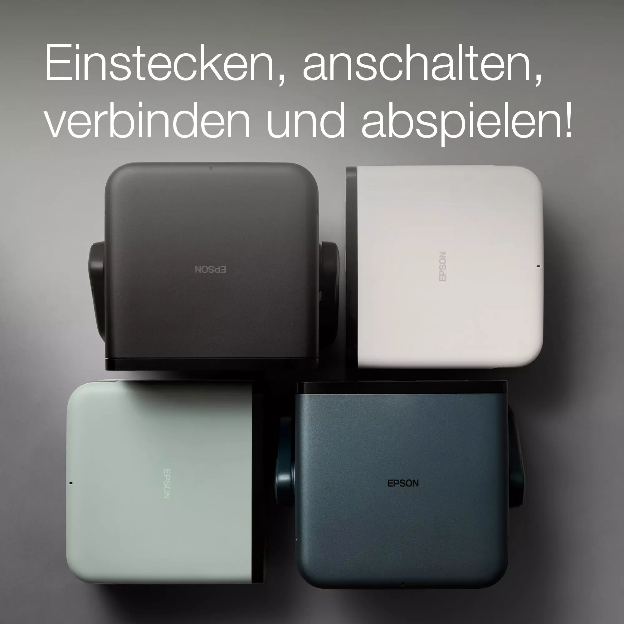 Vier quadratische Projektoren in verschiedenen Farben auf grauem Hintergrund. Text: Einstecken, anschalten, verbinden und abspielen!