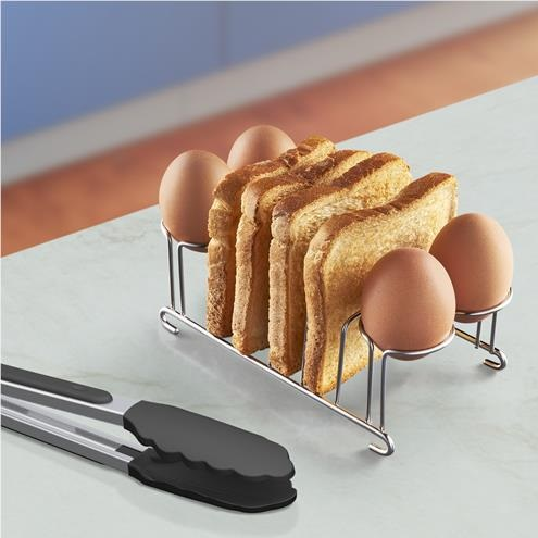 Stojak z chlebem i jajkami, obok szczypiec. Ustawienie znajduje się na białej powierzchni.