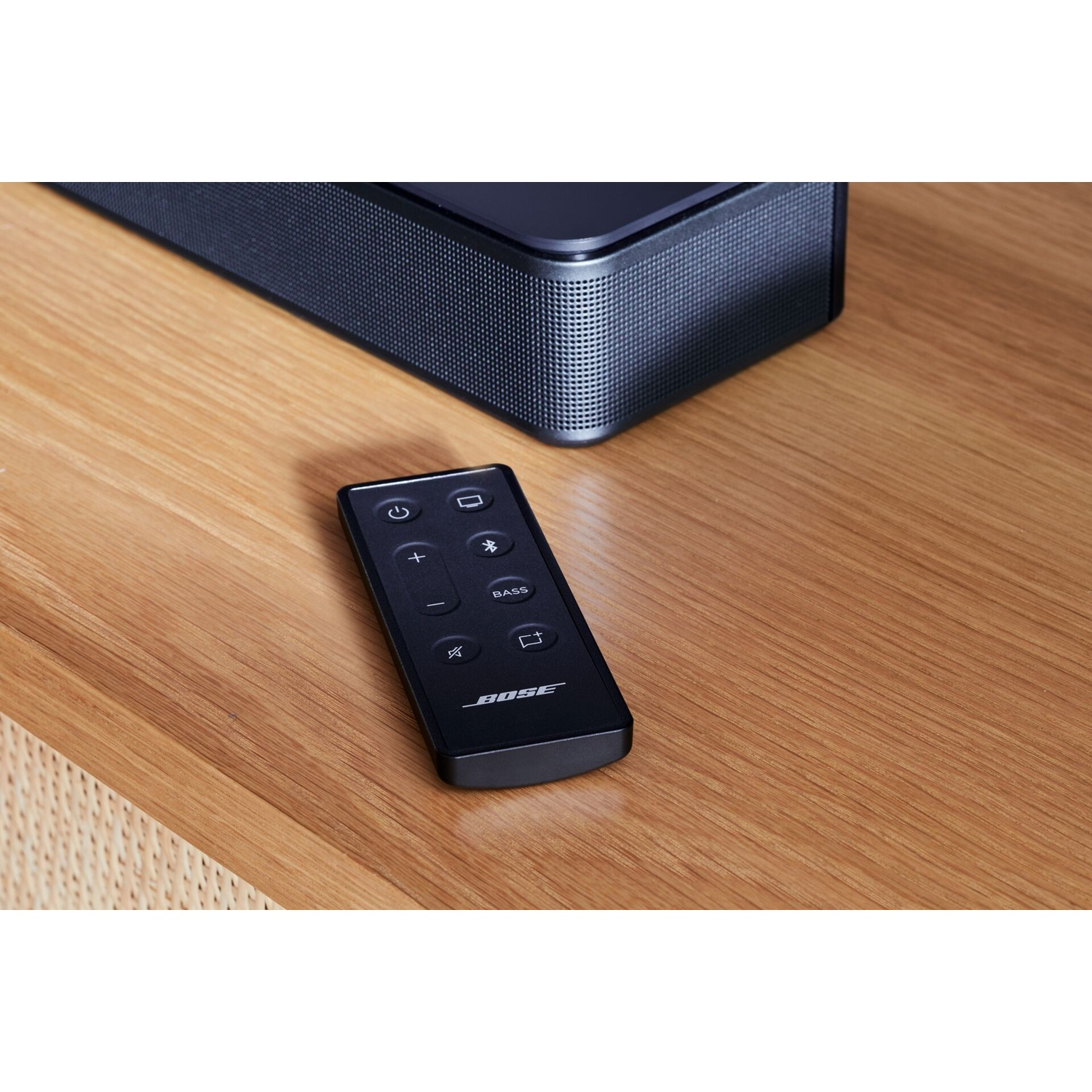 Soundbar Bose e telecomando, superficie in legno.