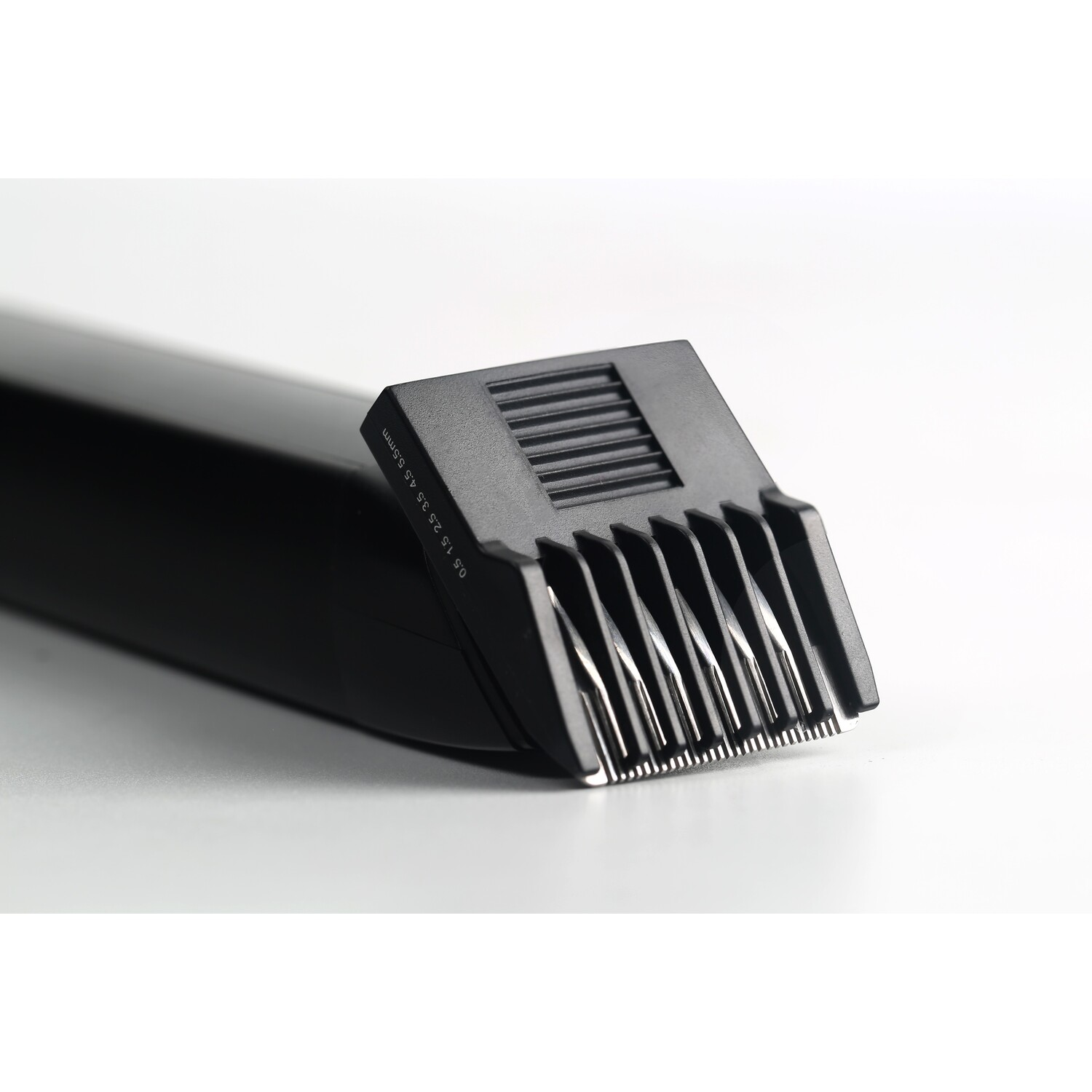 Close-up of a black beard trimmer head with guide combs and a white background.