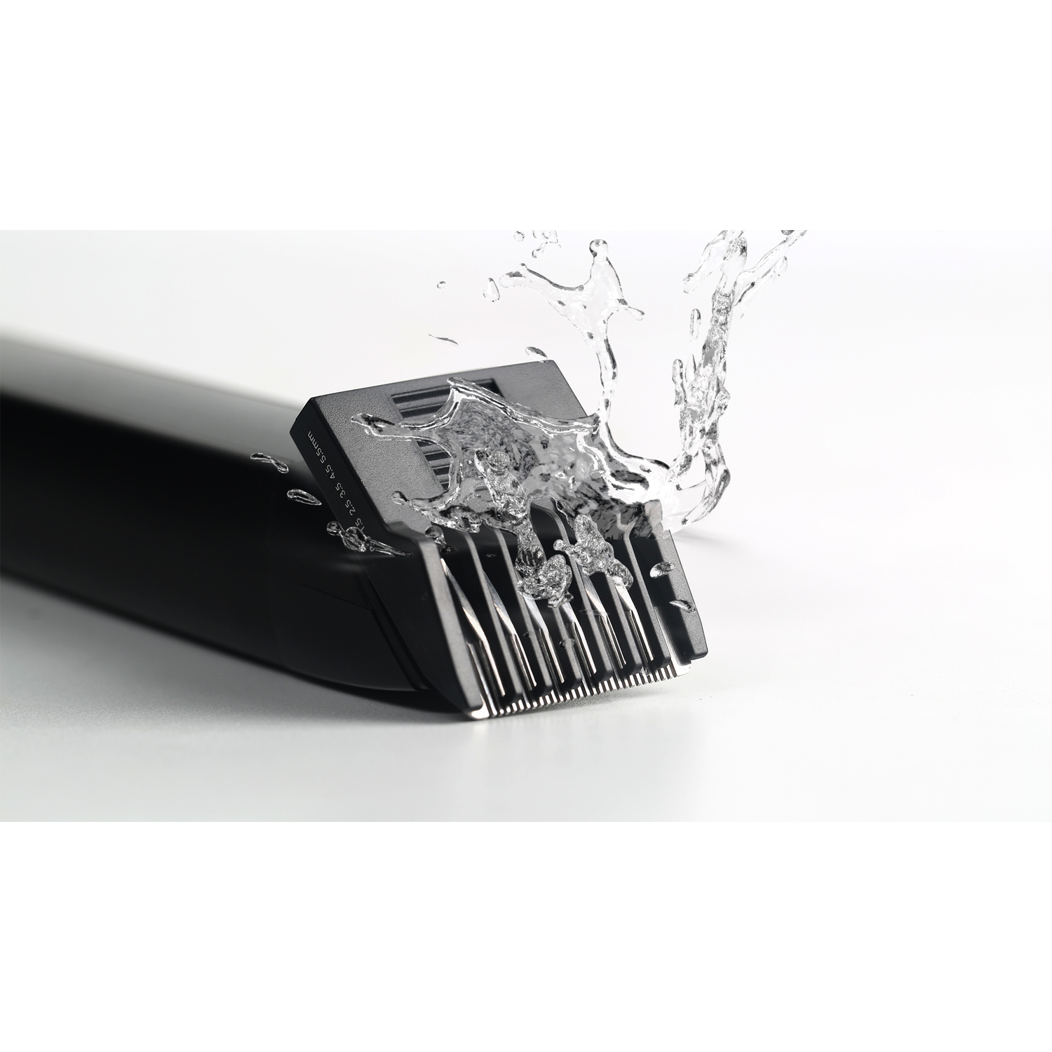 Hair clipper detail, water splashing onto the blades. White background.
