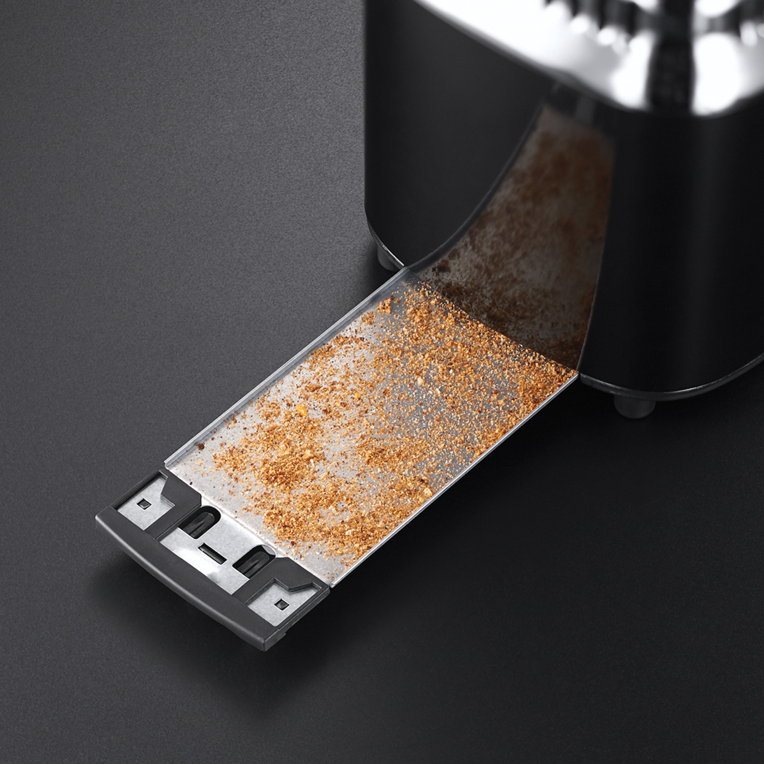 Toaster tray with crumbs, extracted from a black toaster.