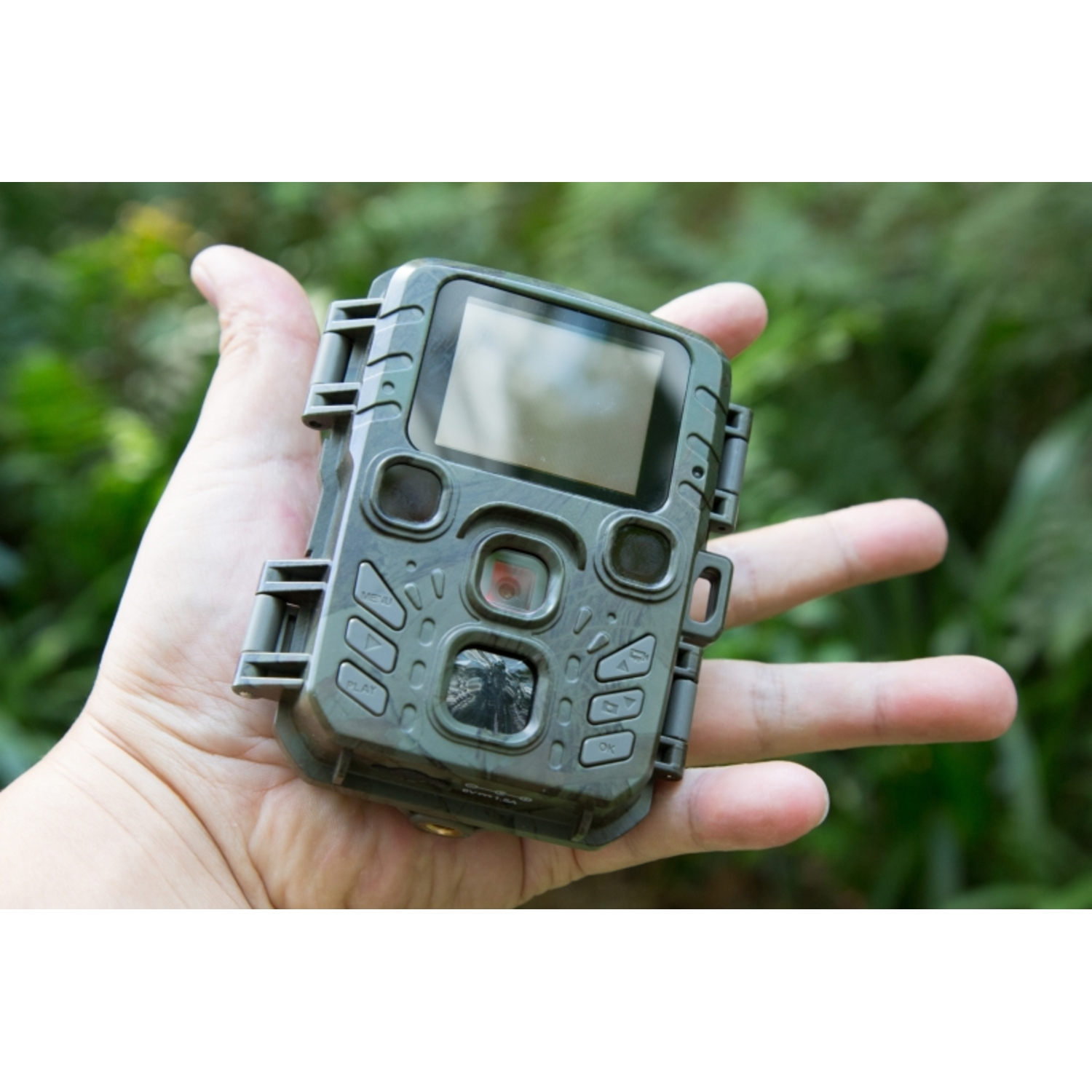 Hand die een wildcamera vasthoudt. Het heeft een scherm, knoppen en een lens.