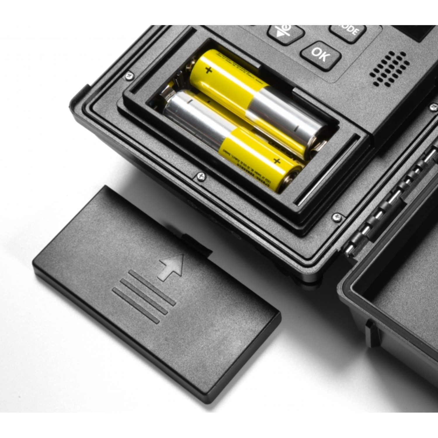 Open batterijcompartiment met twee gele batterijen in een zwart apparaat.