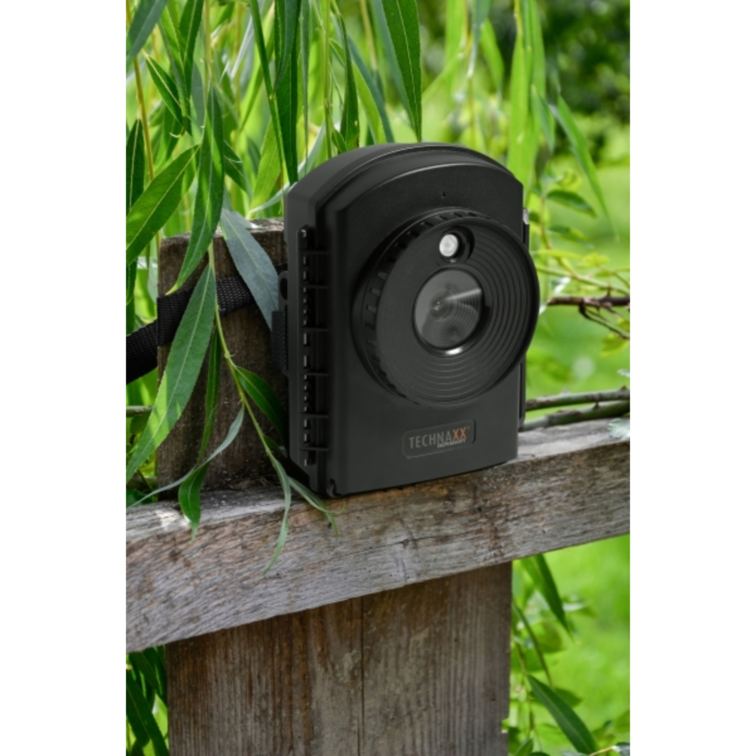 Zwarte wildcamera gemonteerd op een houten hek.