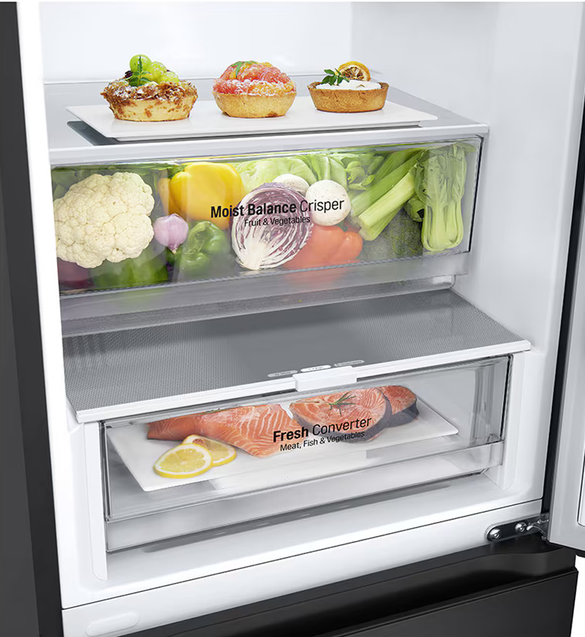 Wnętrze lodówki. Są szuflady z jedzeniem i pojemnikami. Widoczne są warzywa i gotowe posiłki.