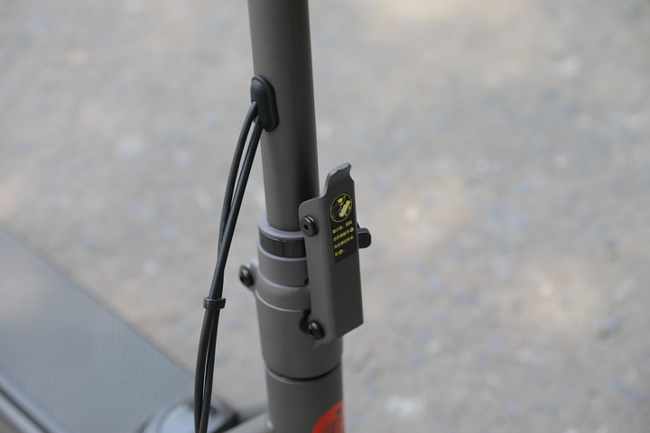 Zbliżenie mechanizmu składania skutera, z dźwignią blokującą i kablem.