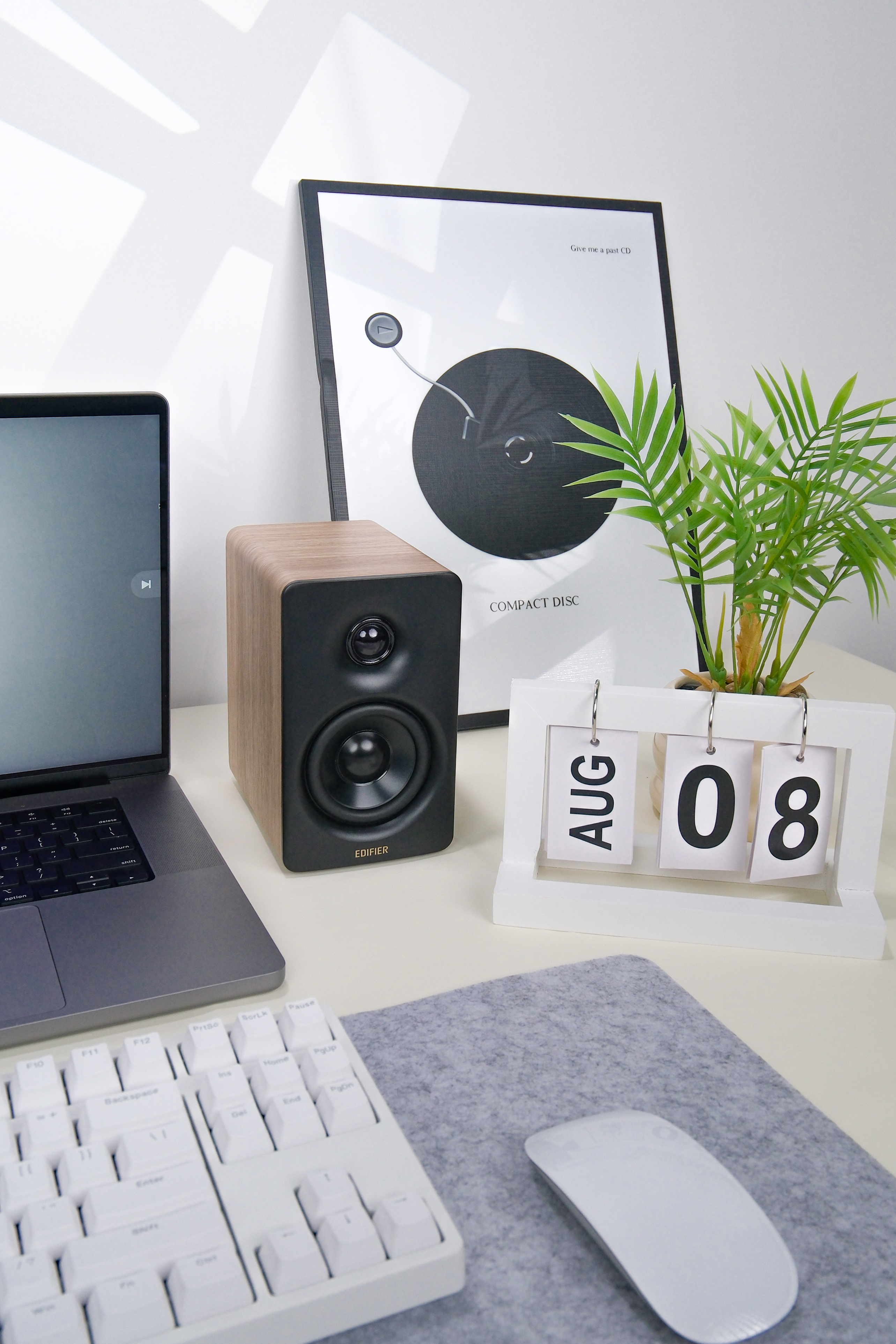 Schreibtisch mit Lautsprecher, Laptop, Tastatur, Maus, Kalender mit 8. August und Pflanze.