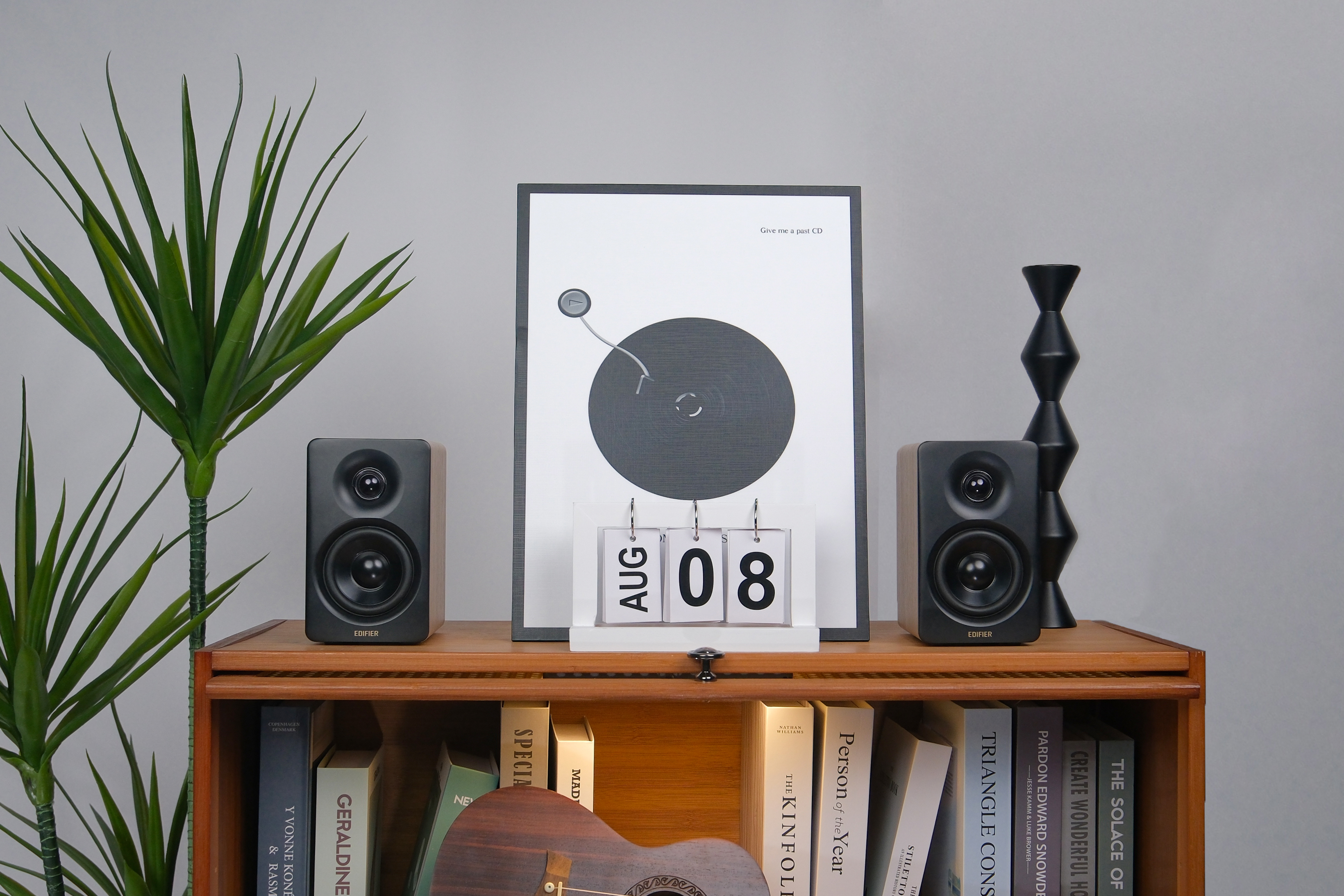 Ein Holzschrank mit einem Lautsprecher auf jeder Seite eines gerahmten Bildes und einem Kalender.