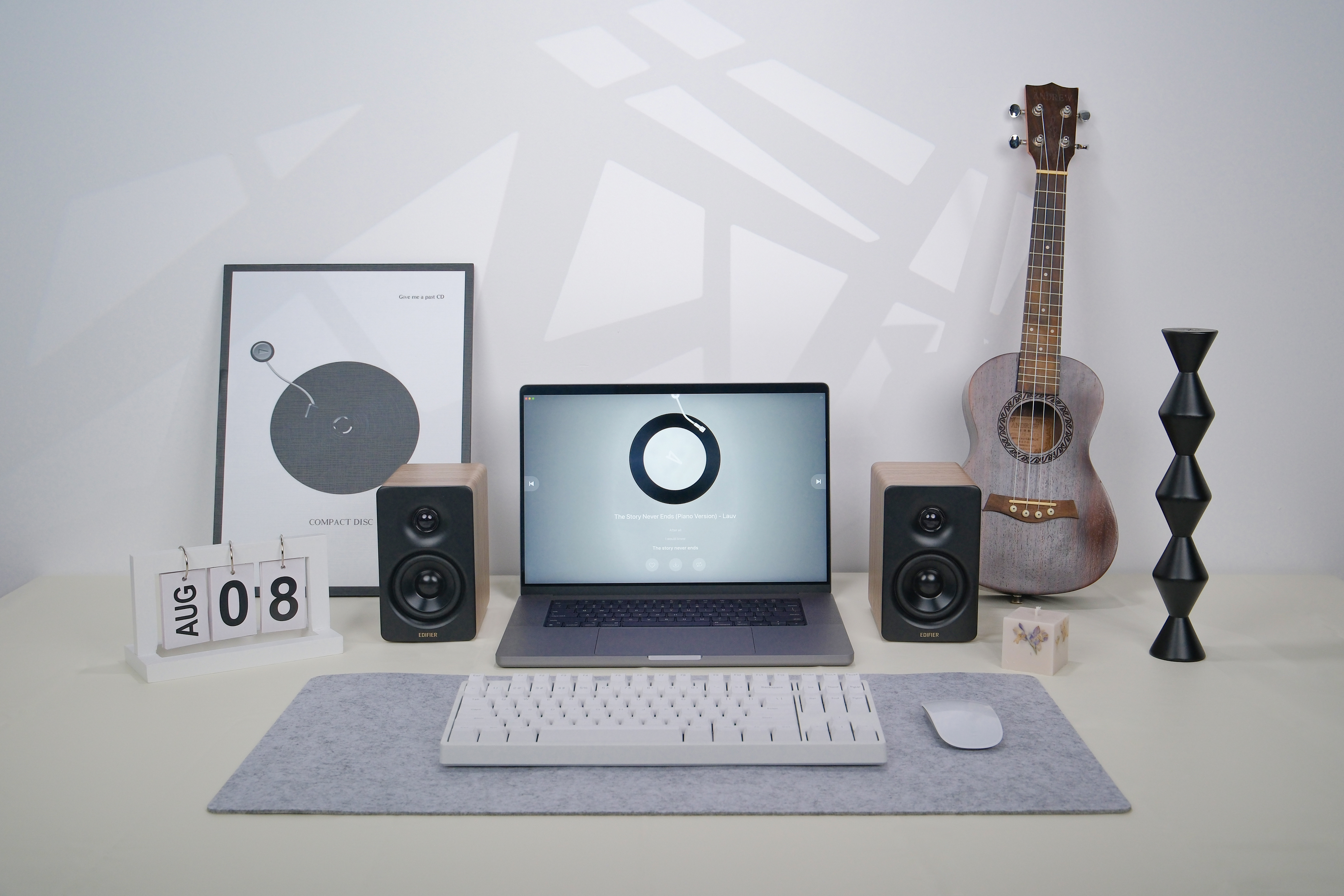 Laptop, Lautsprecher, Tastatur, Maus, Kalender und Ukulele auf einem Schreibtisch, weißer Hintergrund.