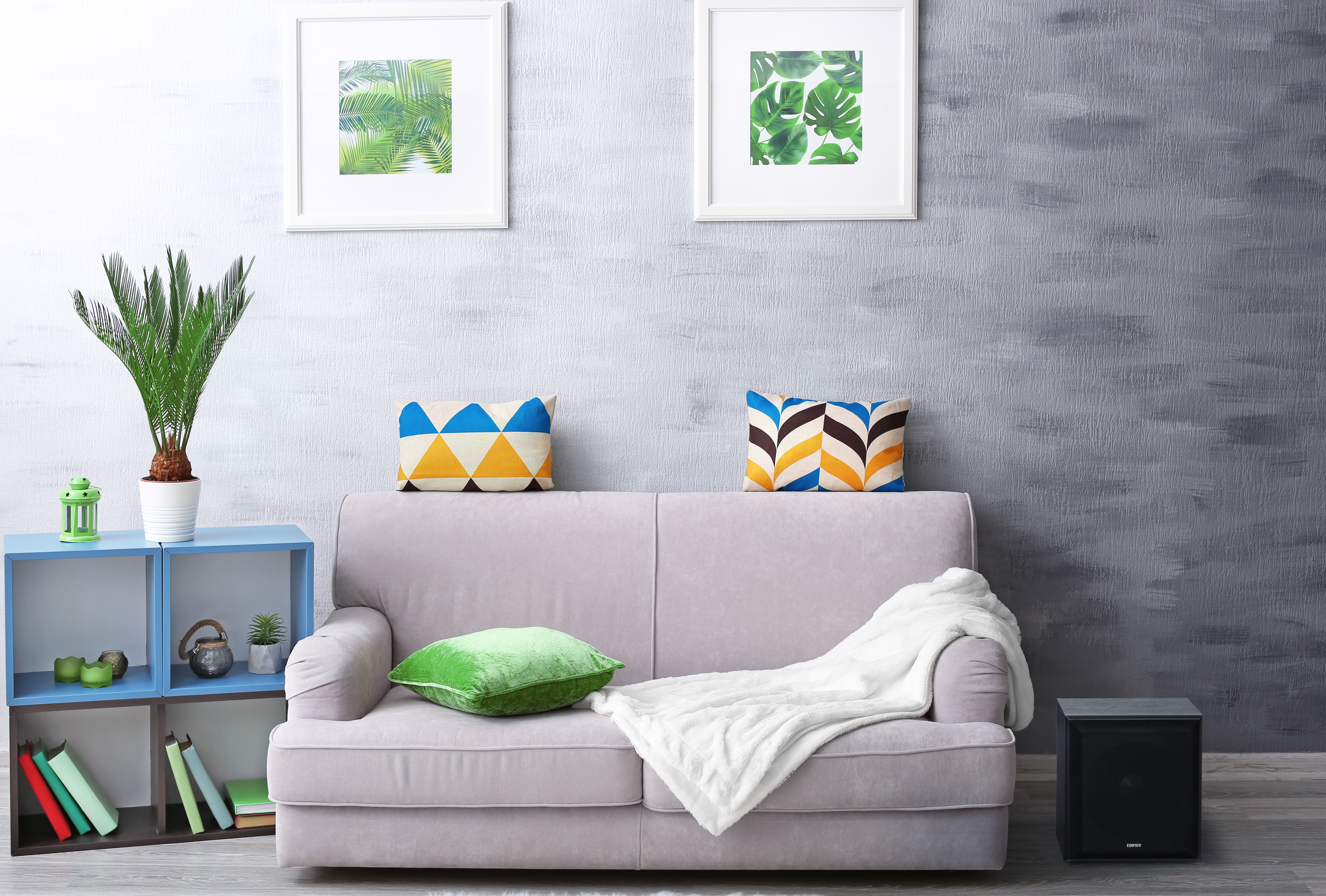 Wohnzimmer mit Sofa, Kissen, Kunst und einem kleinen Lautsprecher.