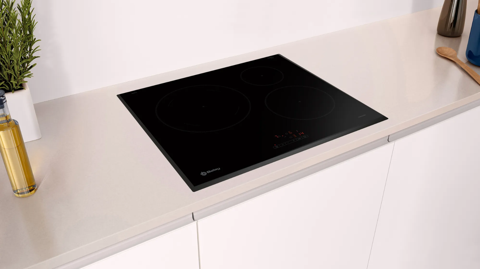 Placa de inducción negra sobre encimera blanca en una cocina moderna.
