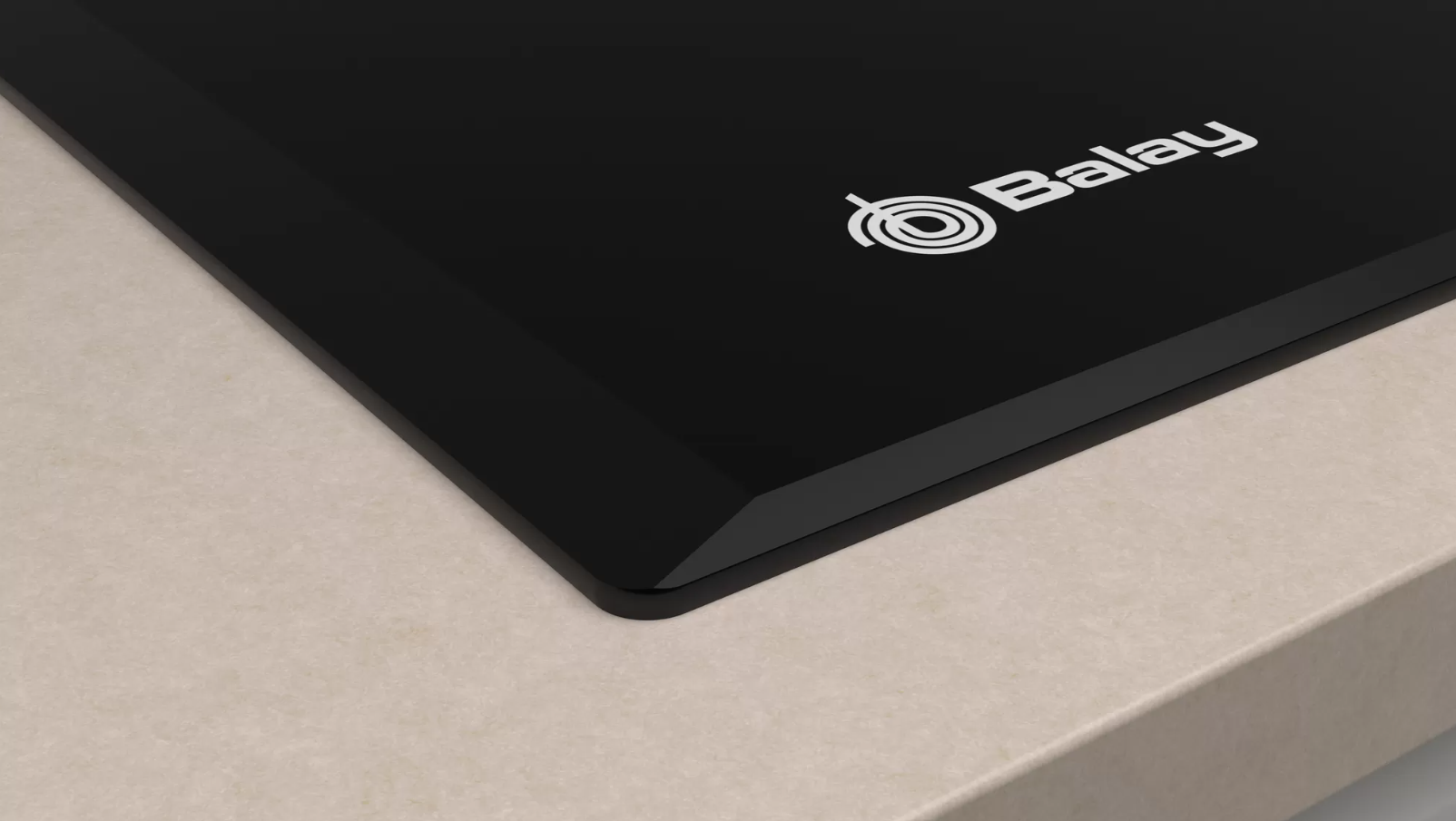 Primer plano de una placa de inducción negra con un logotipo blanco y una encimera beige.
