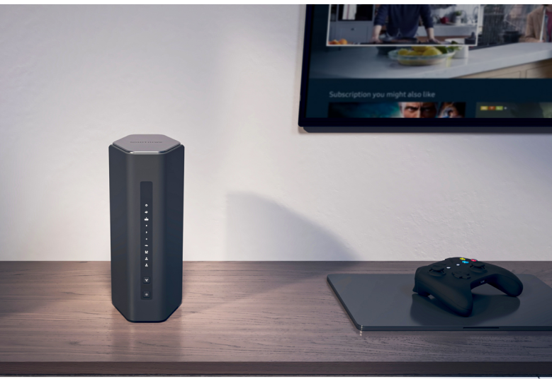 Schwarzes Modem auf einem Tisch mit Laptop und Controller.
