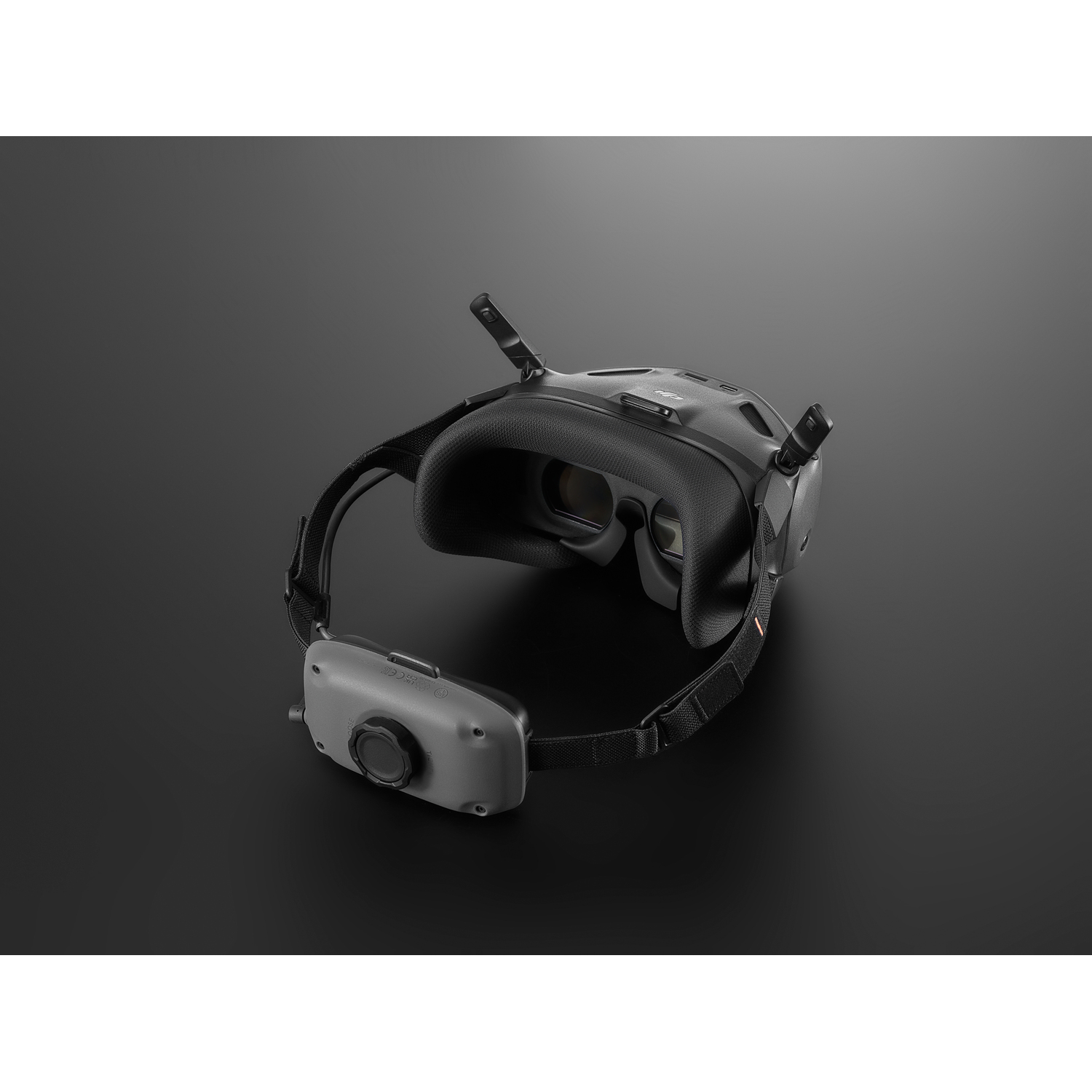 Black VR headset with two antennas and a strap, on a dark surface.