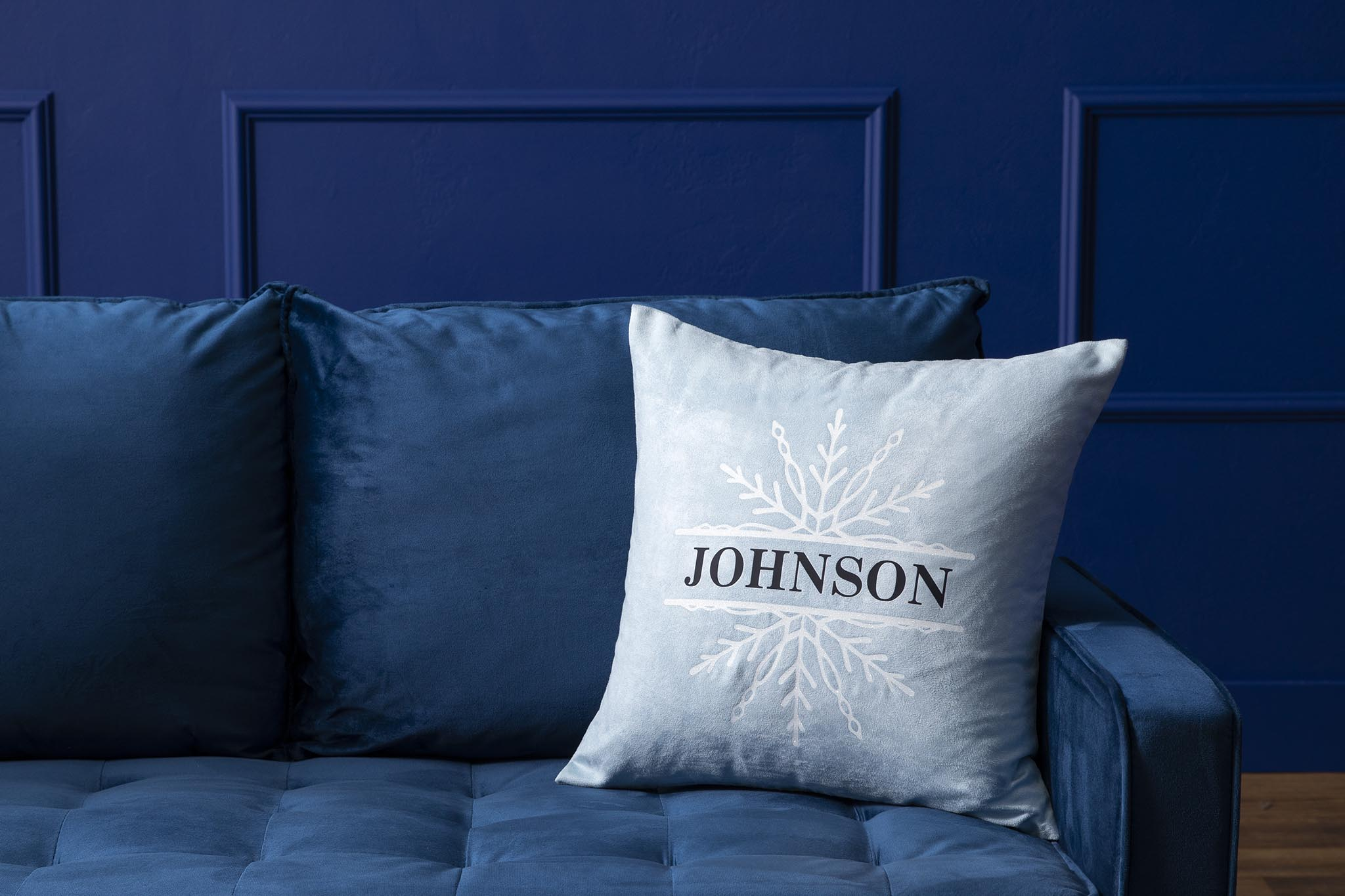 Ein blaues Sofa mit einem Kissen mit einem Schneeflocken-Design und dem Namen 'Johnson'.
