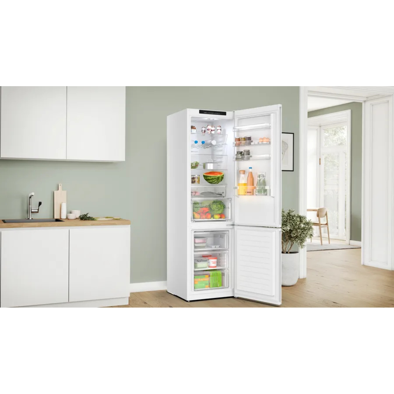 White refrigerator, open. Inside visible: fruits, vegetables, and other food items. Kitchen background.