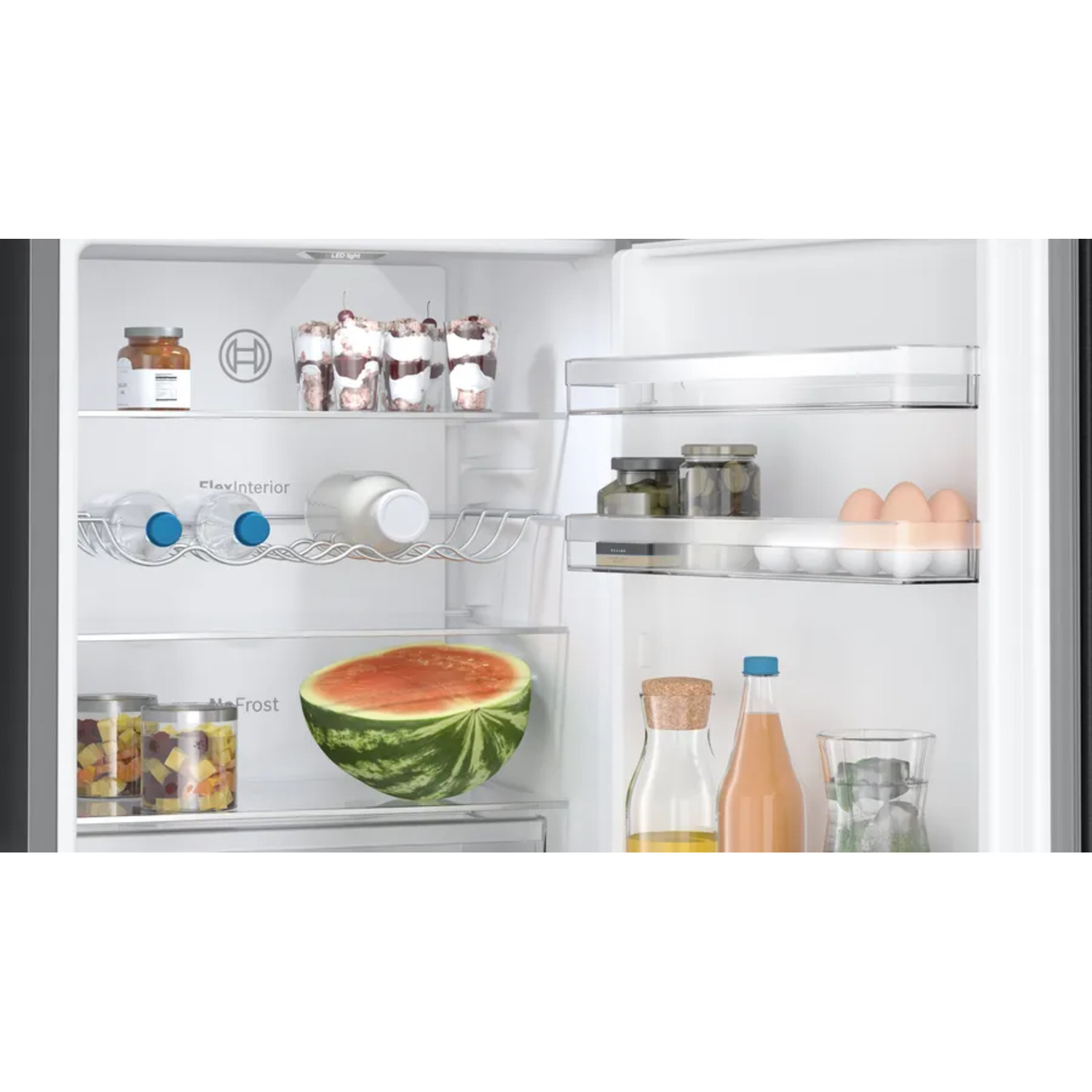 Intérieur du réfrigérateur avec aliments. Pastèque, bouteilles, bocaux et contenants visibles.
