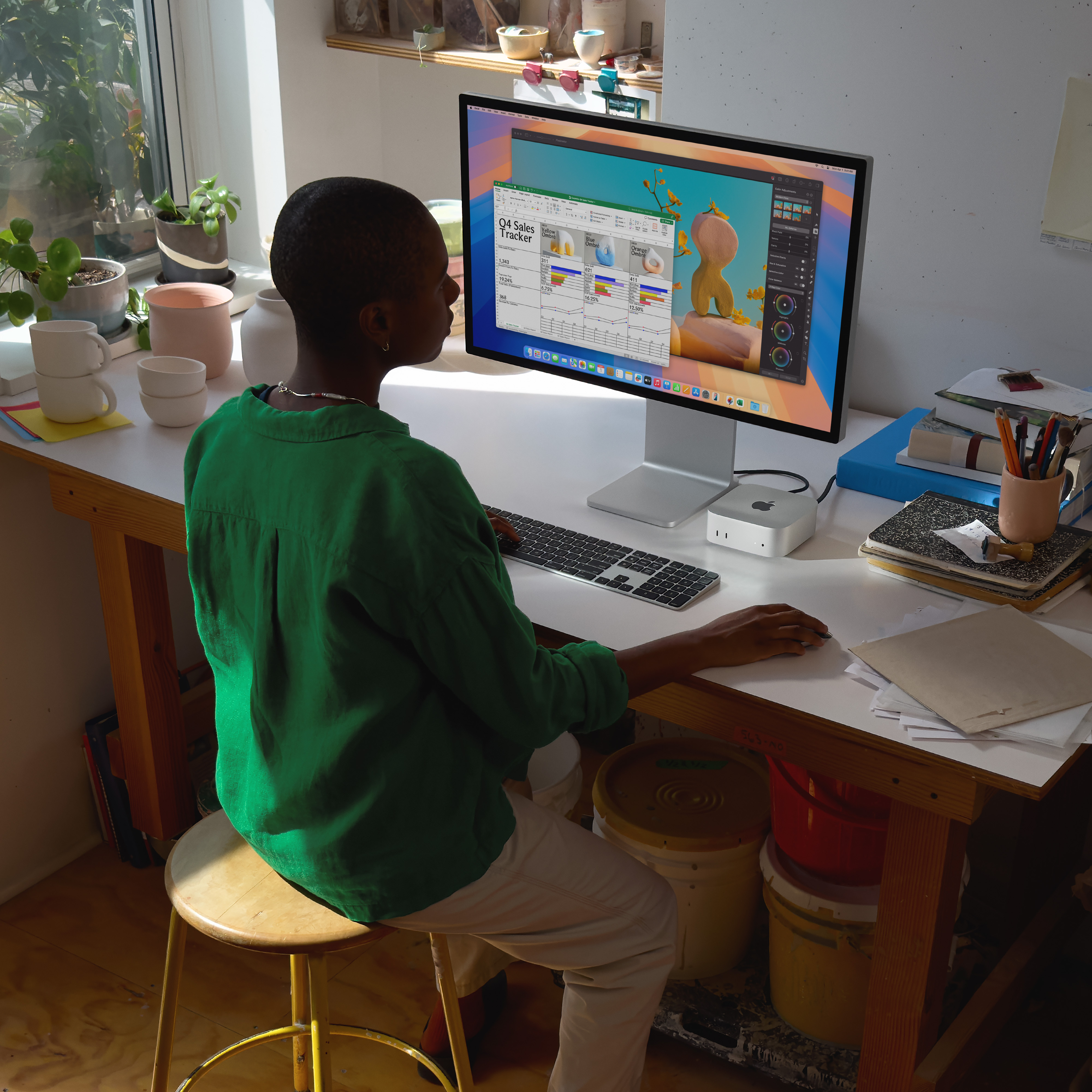 Persona seduta a una scrivania con computer che mostra un foglio di calcolo. Fogli e tazze sulla scrivania.