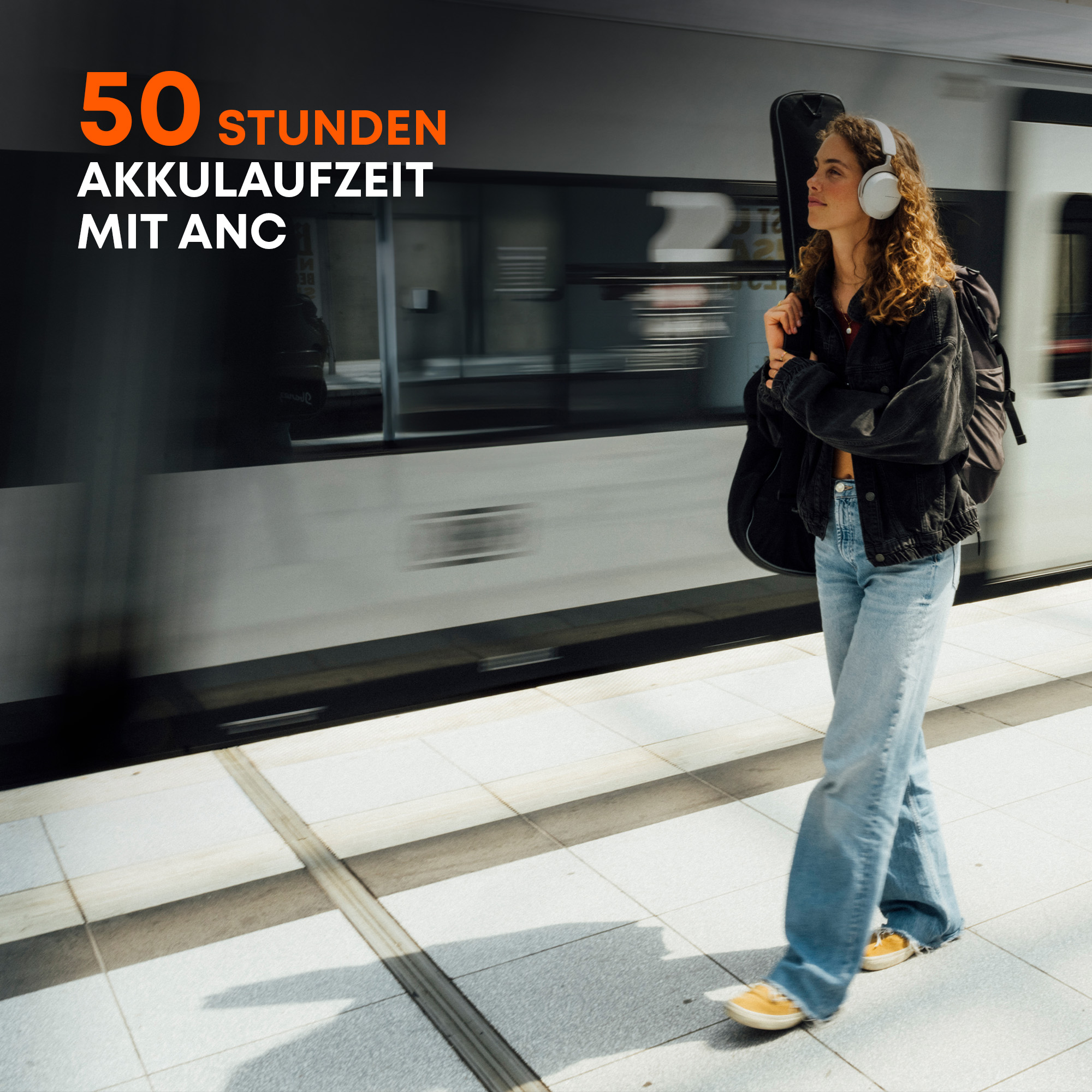 Frau mit Kopfhörern, geht auf einem Bahnsteig, Text über Akkulaufzeit.