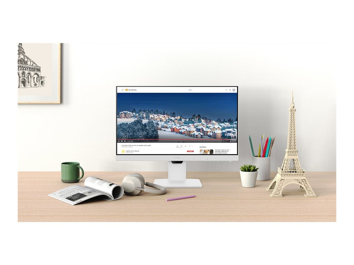 Ein Schreibtisch mit Monitor, Kopfhörern und einem Buch, mit einem Eiffelturm-Modell.