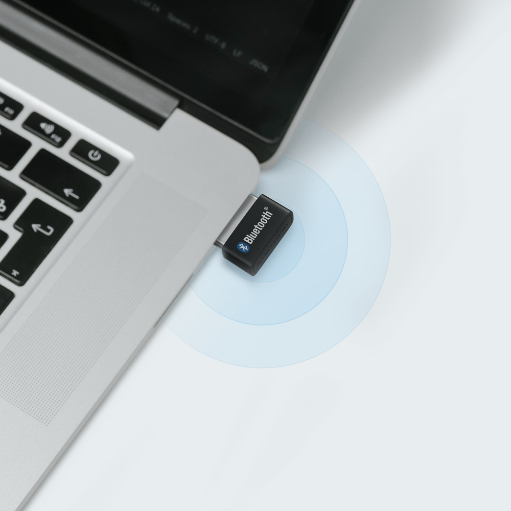 Bluetooth adaptörü takılı bir dizüstü bilgisayar. Adaptör siyah renkte.
