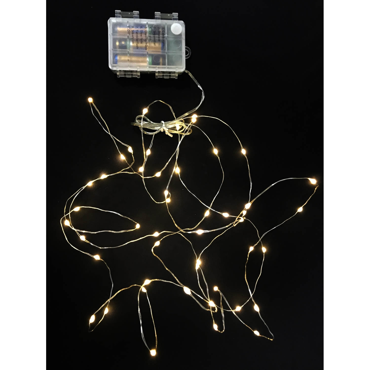 Luci a filo con piccoli LED su una superficie nera. È visibile anche un pacco batterie.