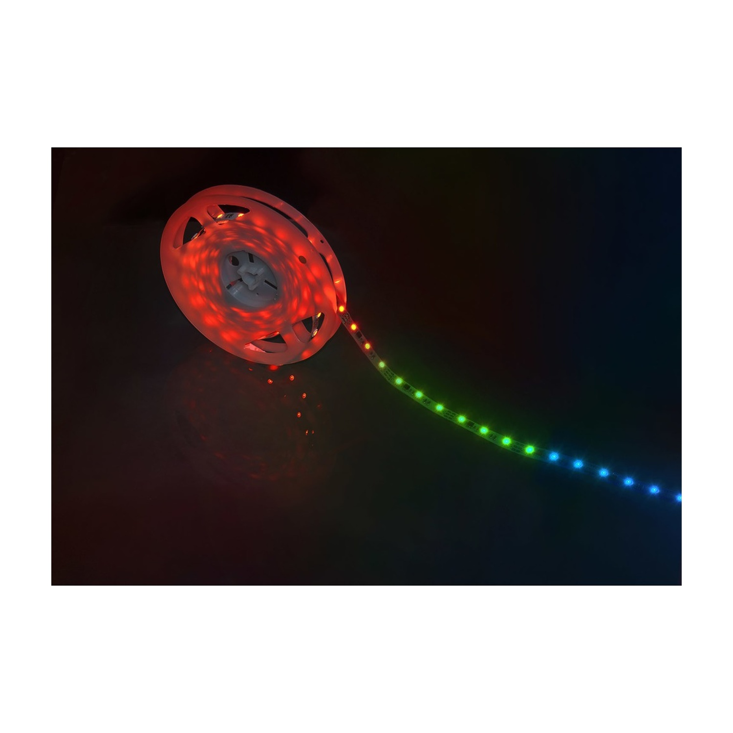 Rotolo di strisce luminose a LED. La striscia è rossa, verde e blu, con luci accese, su uno sfondo scuro.