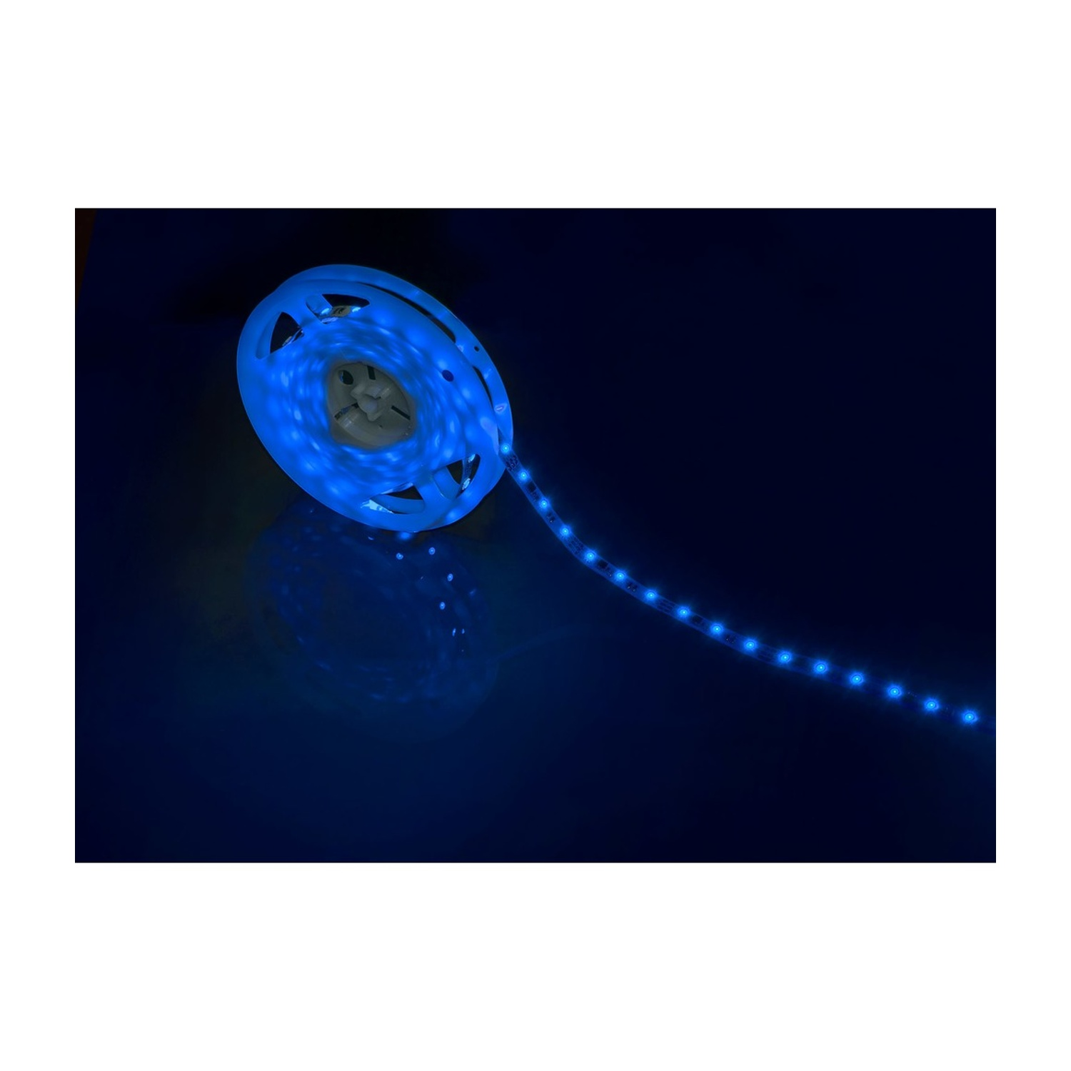 Striscia LED blu. Arrotolata ed emette luce blu. Sfondo scuro con riflessi.