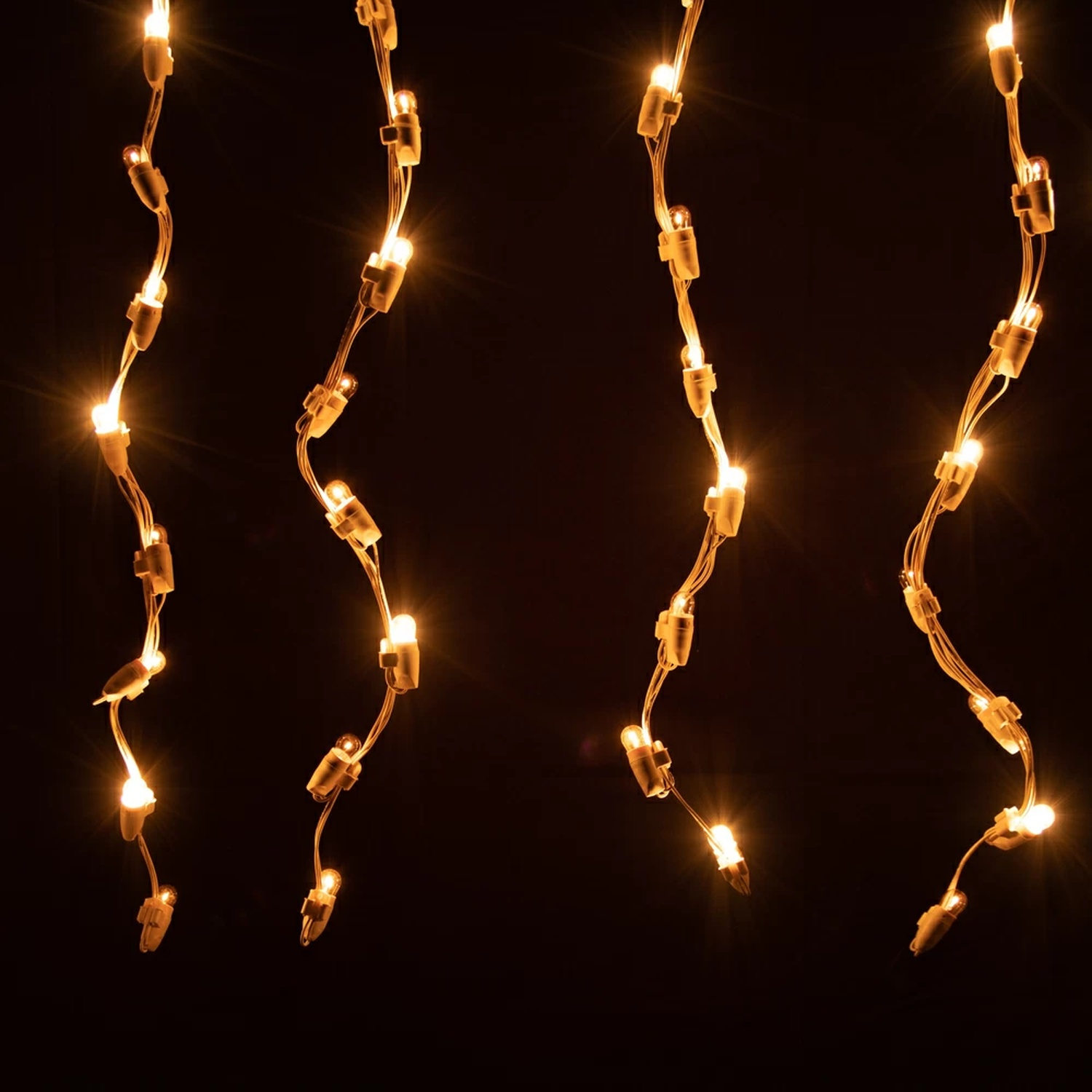 Quattro fili di luci appese su sfondo scuro. Ognuno ha piccole luci.