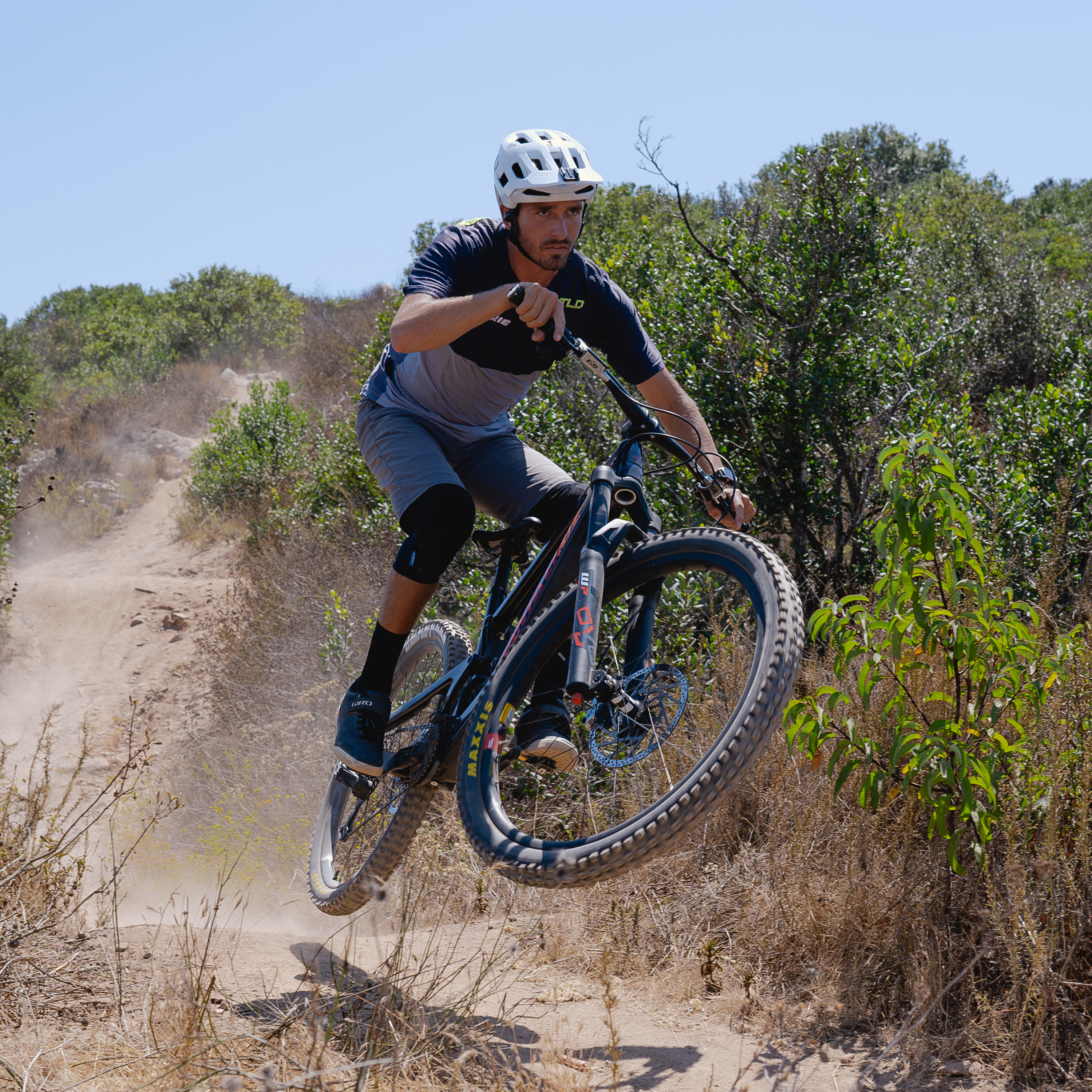 Egy férfi mountain bike-ozik egy földúton, a levegőbe ugorva.