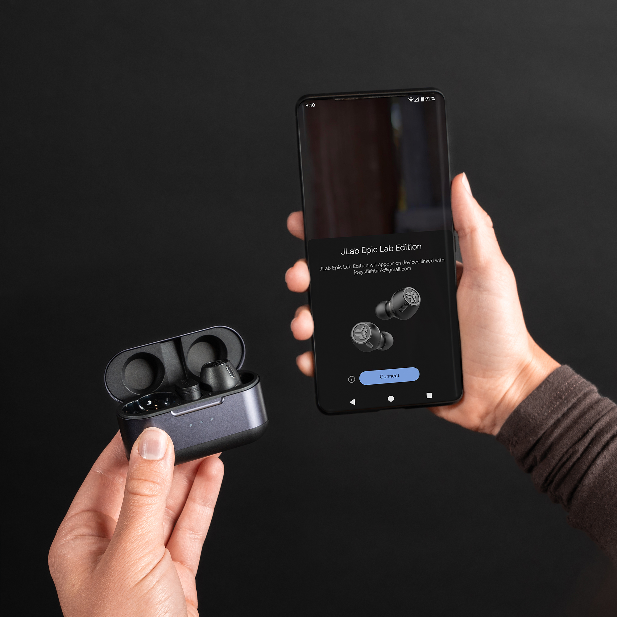 Kézben egy töltőtok és egy telefon. A telefonon fülhallgatók láthatók a 'Connect' gombbal.