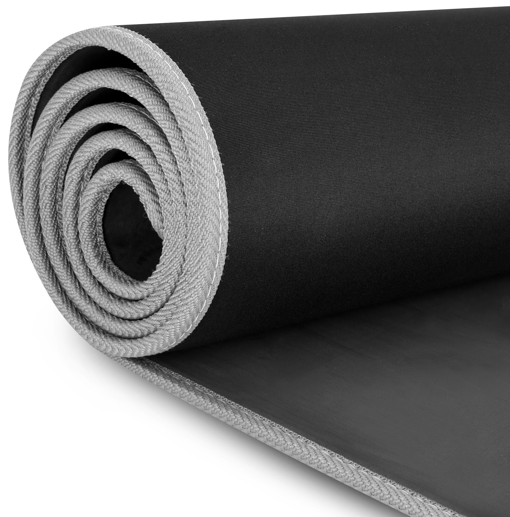 Zwinięta czarna mata z szarymi obrzeżami na białej powierzchni.