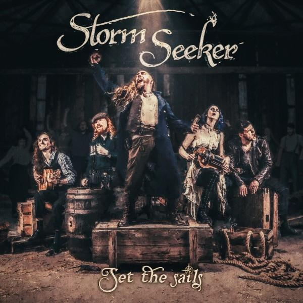 Albumcover mit der Band Storm Seeker. Bandmitglieder auf der Bühne, einige spielen Instrumente.
