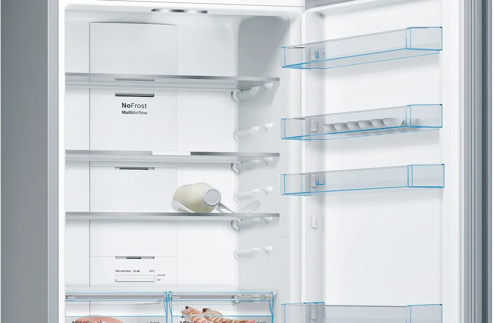Wnętrze otwartej lodówki z półkami, pojemnikiem i jedzeniem. Tekst: NoFrost MultiAirflow.