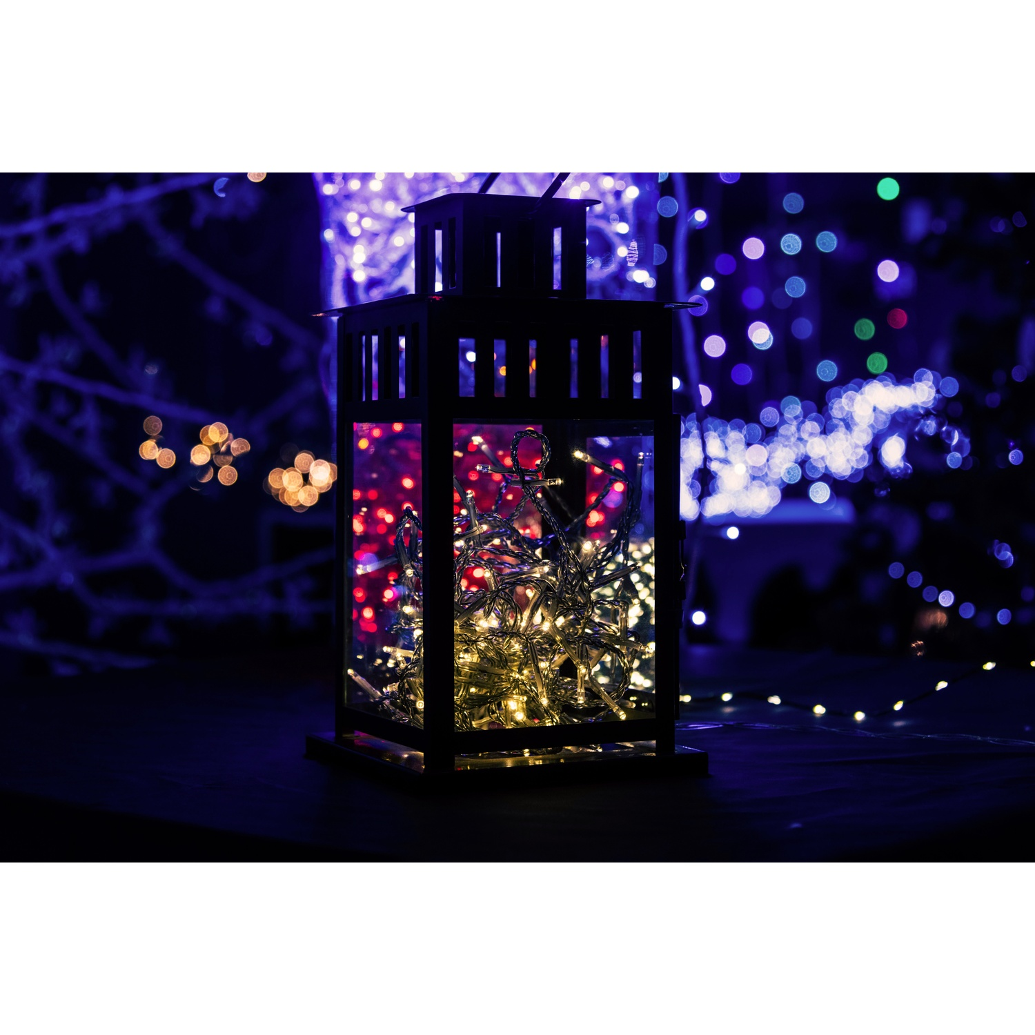 Una lanterna decorativa con luci all'interno, su uno sfondo scuro e sfocato.
