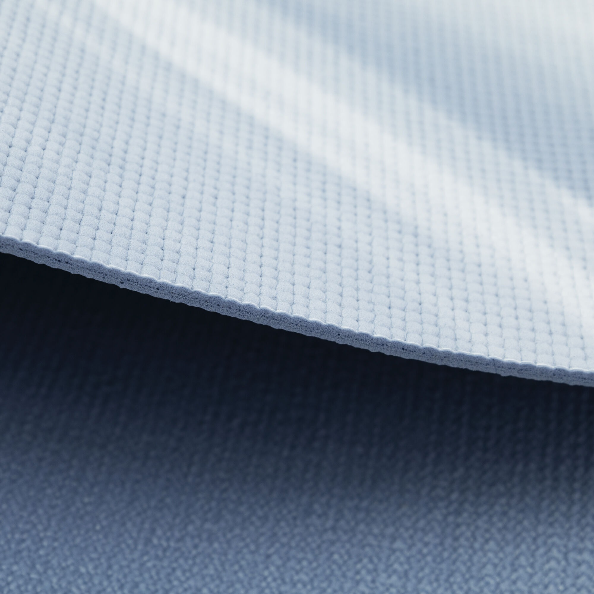 Zbliżenie jasnoniebieskiej maty do jogi, z widoczną fakturą powierzchni.