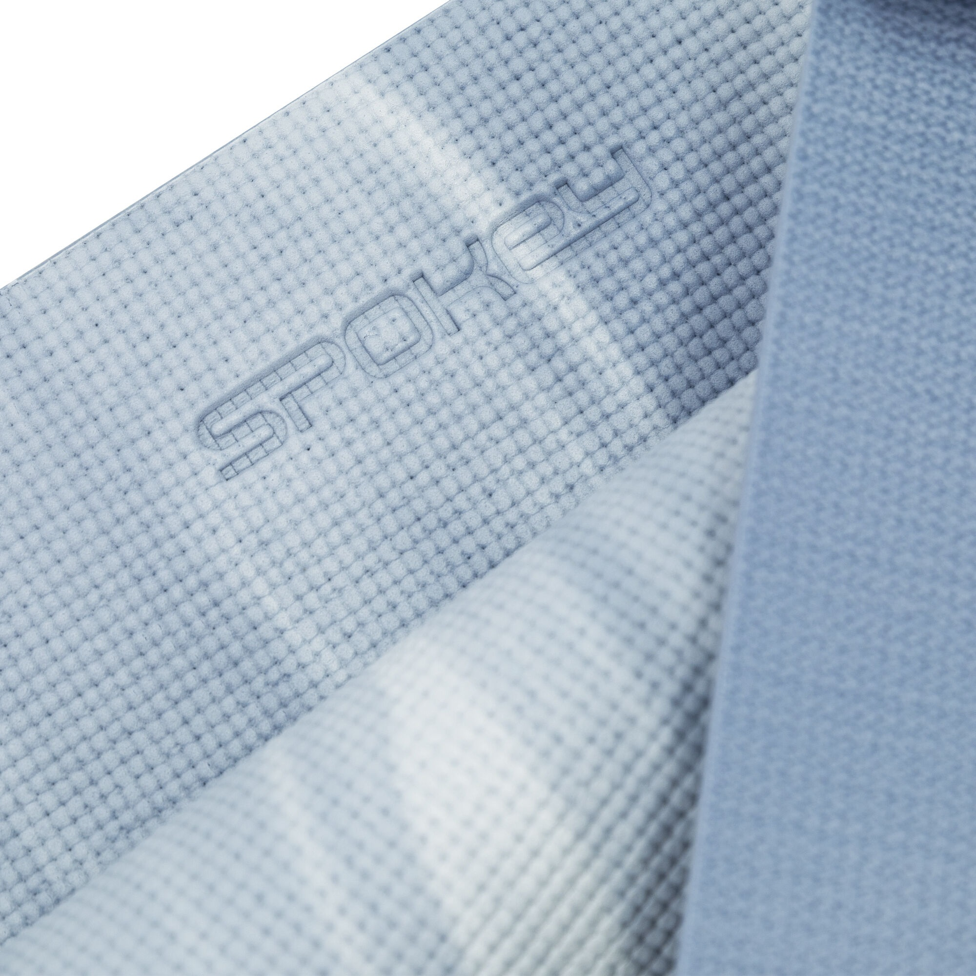 Zbliżenie niebieskiej maty do jogi z wytłoczonym napisem 'SPOKEY'.