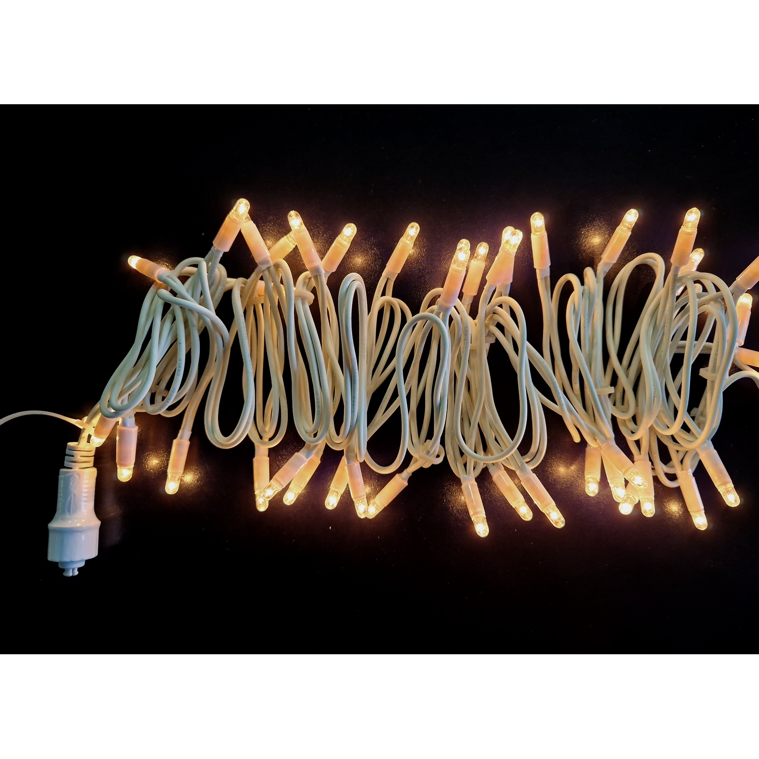Catena di luci con filo bianco e luci su sfondo nero.