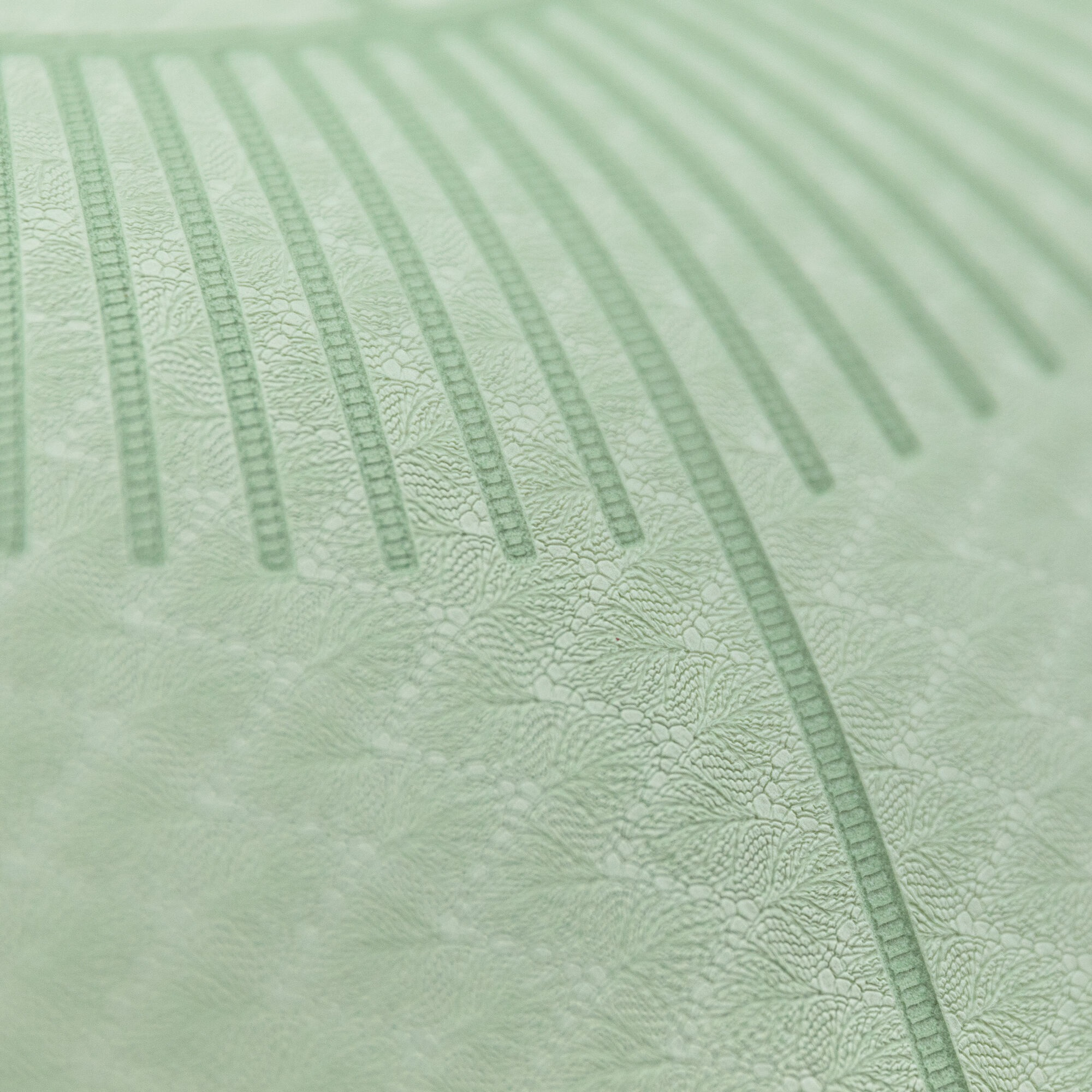 Zbliżenie zielonej, wzorzystej powierzchni z liniowymi i kwiatowymi wzorami.