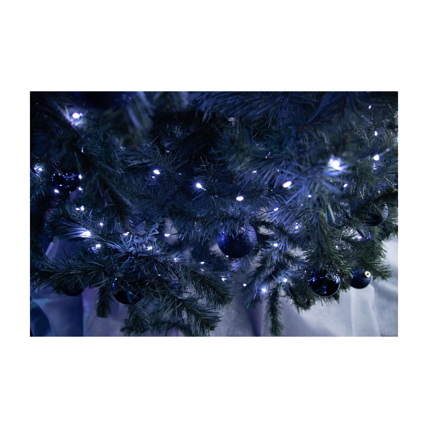 Rami di albero di Natale con luci blu e ornamenti, ripresa dal basso.
