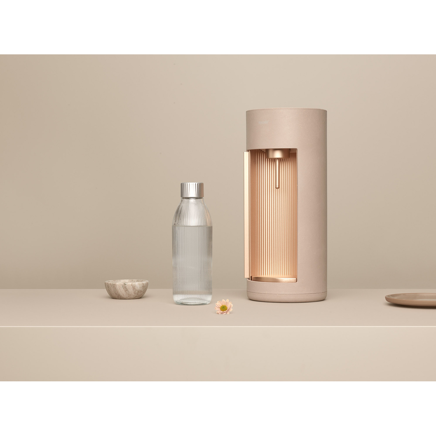 Distributeur d'eau avec bouteille et petit bol sur surface beige.