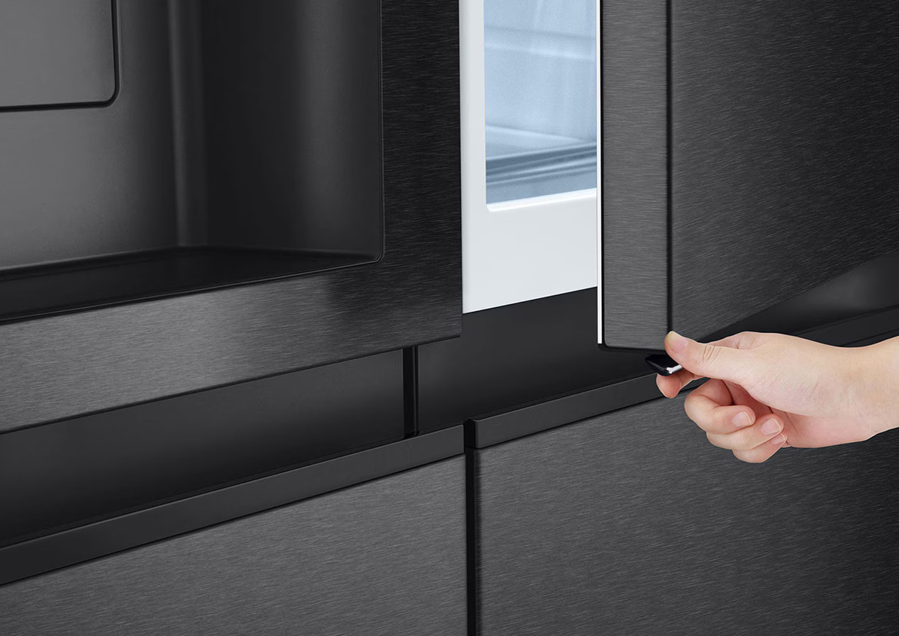 Zbliżenie czarnej lodówki z otwieraną rączką, widoczne światło wewnętrzne.