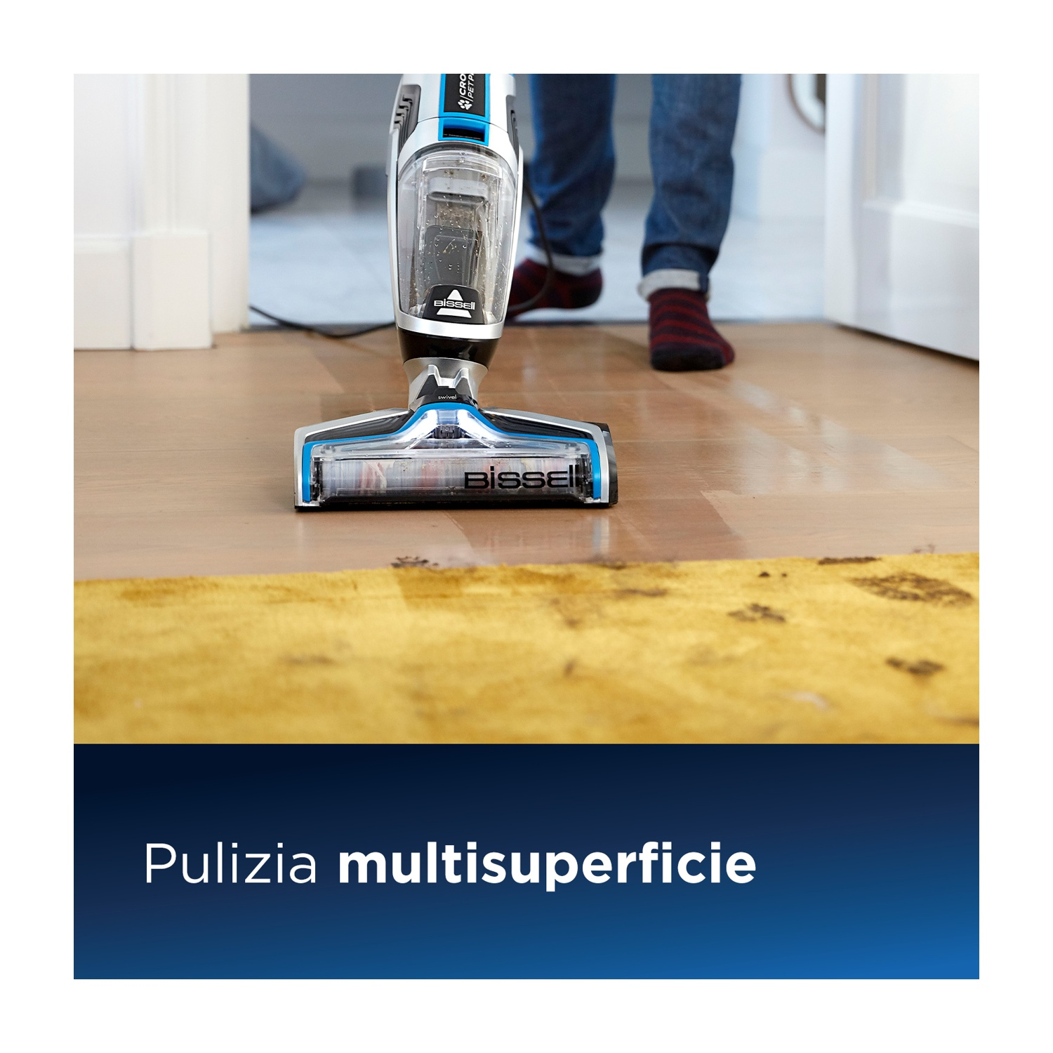 Un aspirapolvere pulisce un pavimento in legno. Il pavimento ha un tappeto giallo.