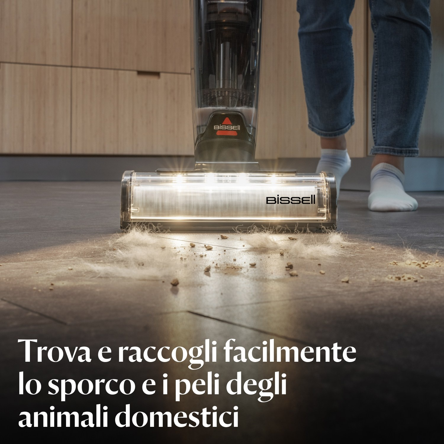 Persona che aspira, raccogliendo sporco e peli di animali su un pavimento grigio, con Bissell.
