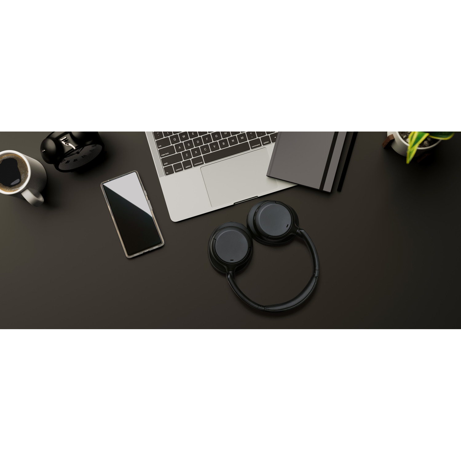 Desk setup with coffee, phone, laptop, headphones, clock, and notebook. Dark surface.