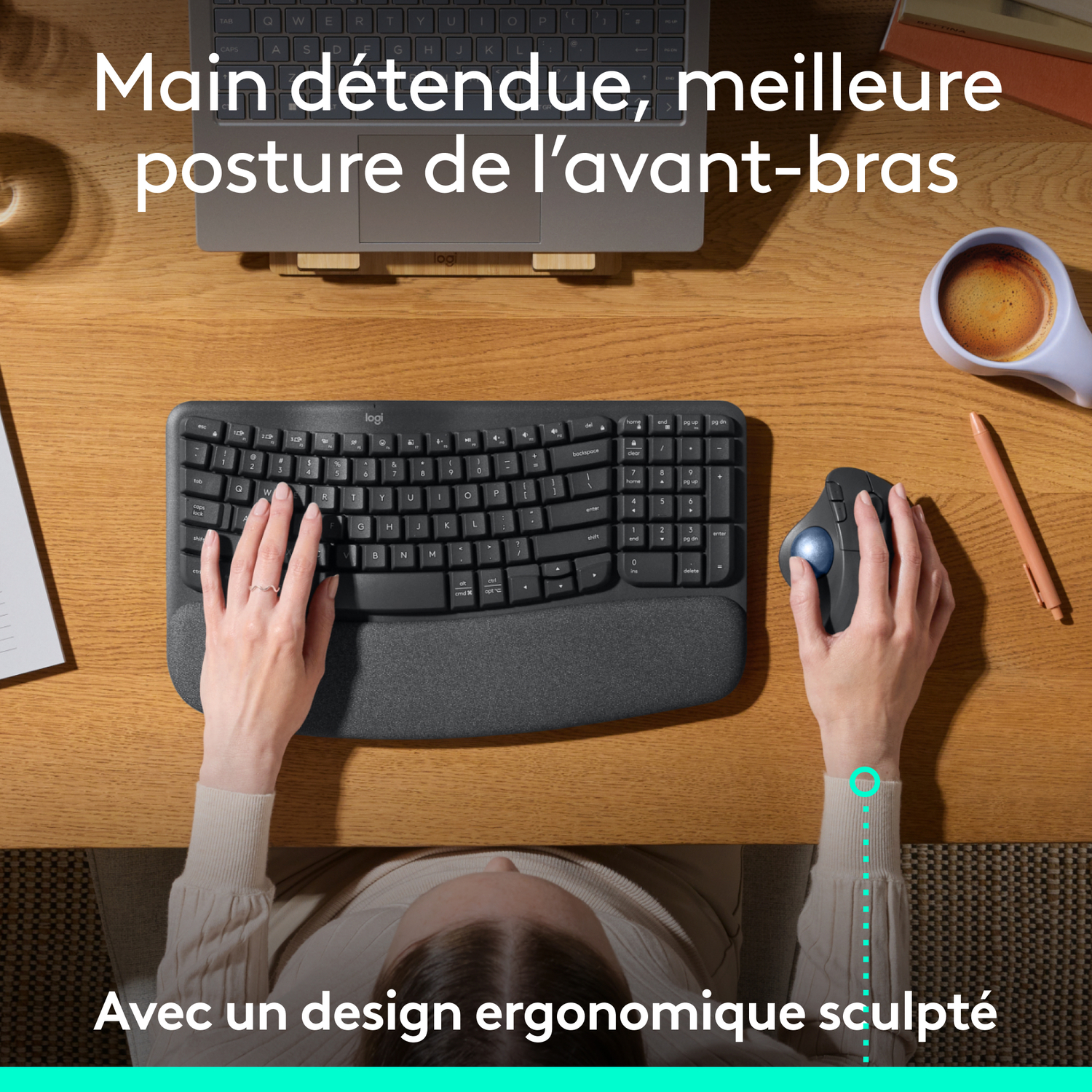 Vue de dessus des mains sur clavier et souris ergonomiques, sur une table en bois.
