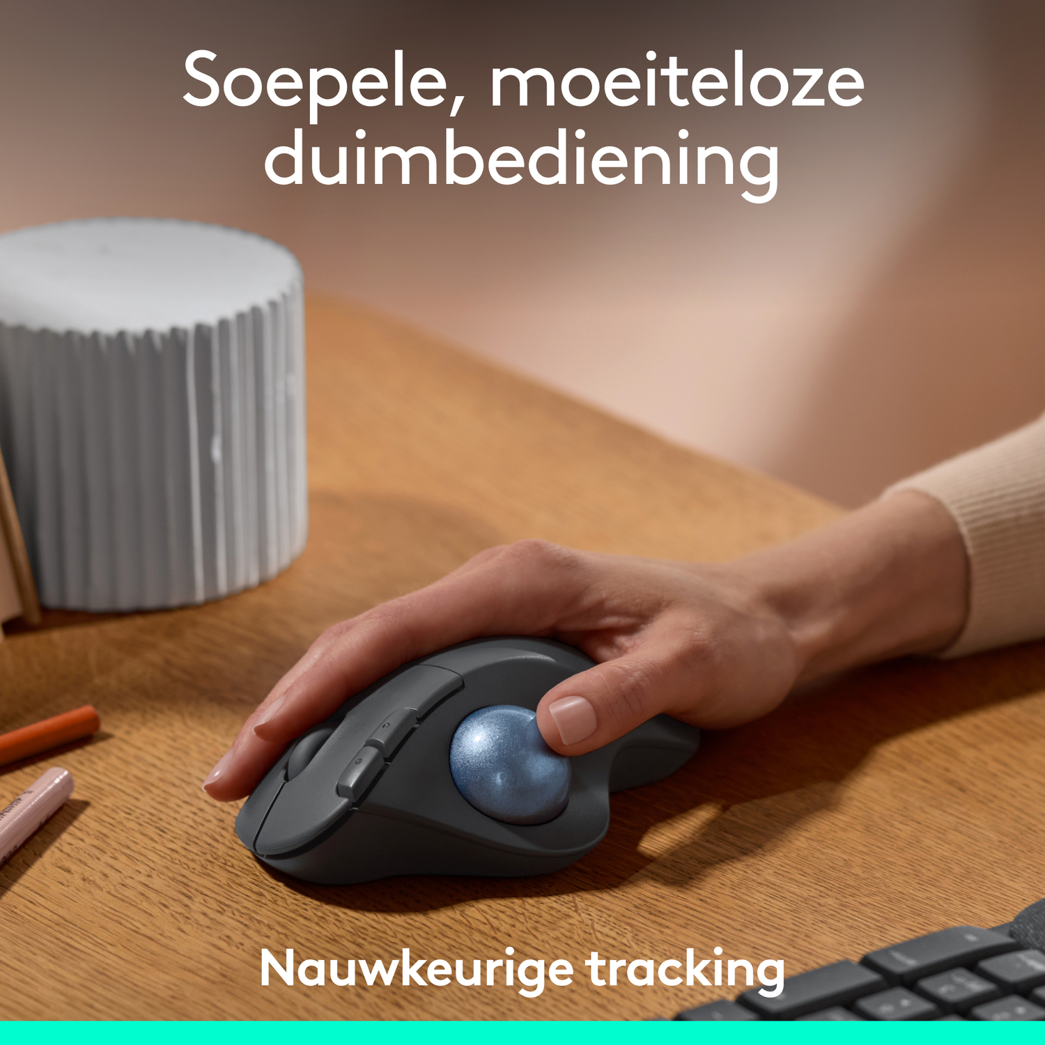 Hand using a trackball mouse on a wooden desk, with text about thumb control.